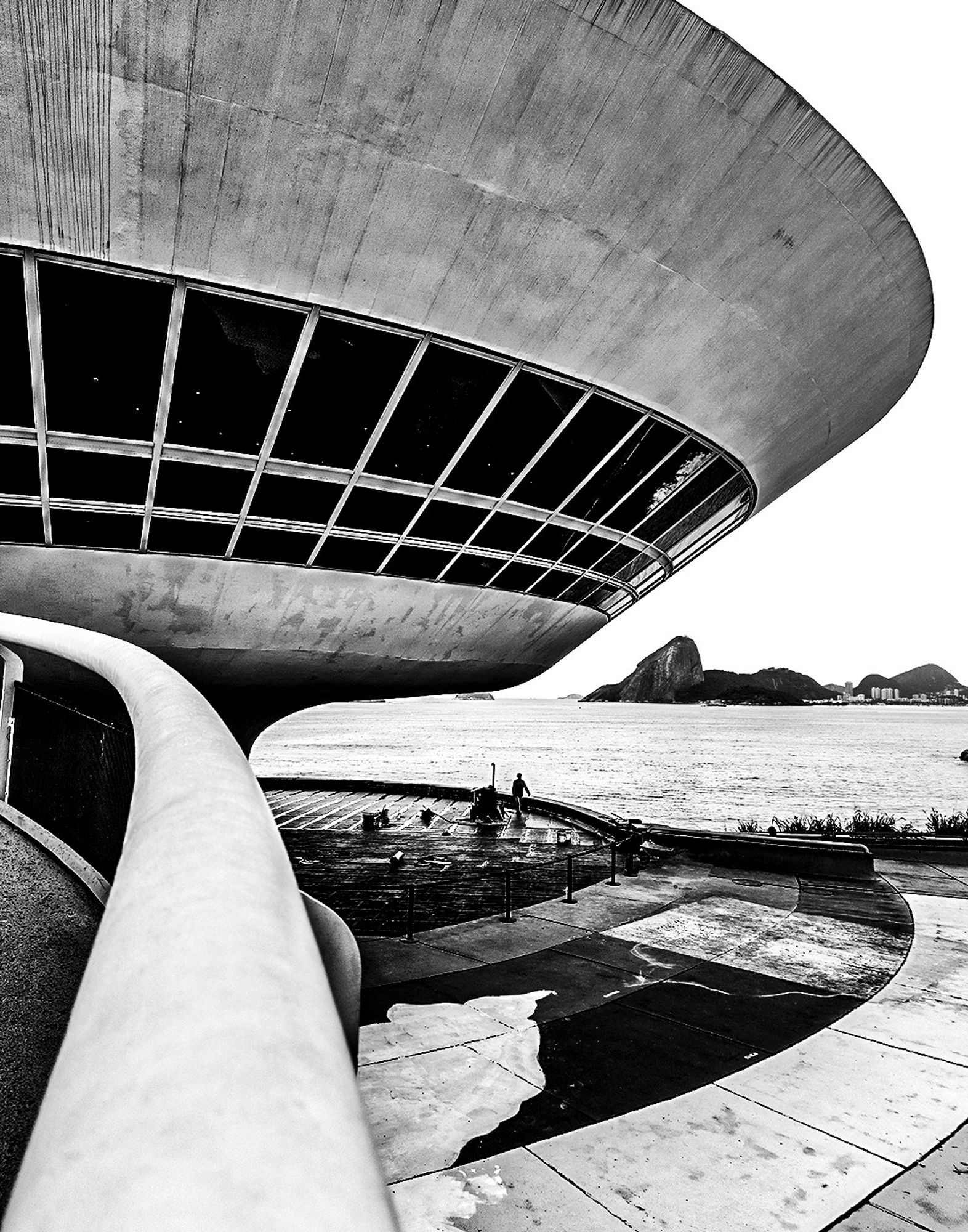 Fotografia em preto e branco do Museu de Arte Contemporânea de Niterói, localizado na cidade de Niterói, no Rio de Janeiro, no Brasil. Inaugurado no dia 2 de setembro de 1996 e projetado pelo arquiteto Oscar Niemeyer.