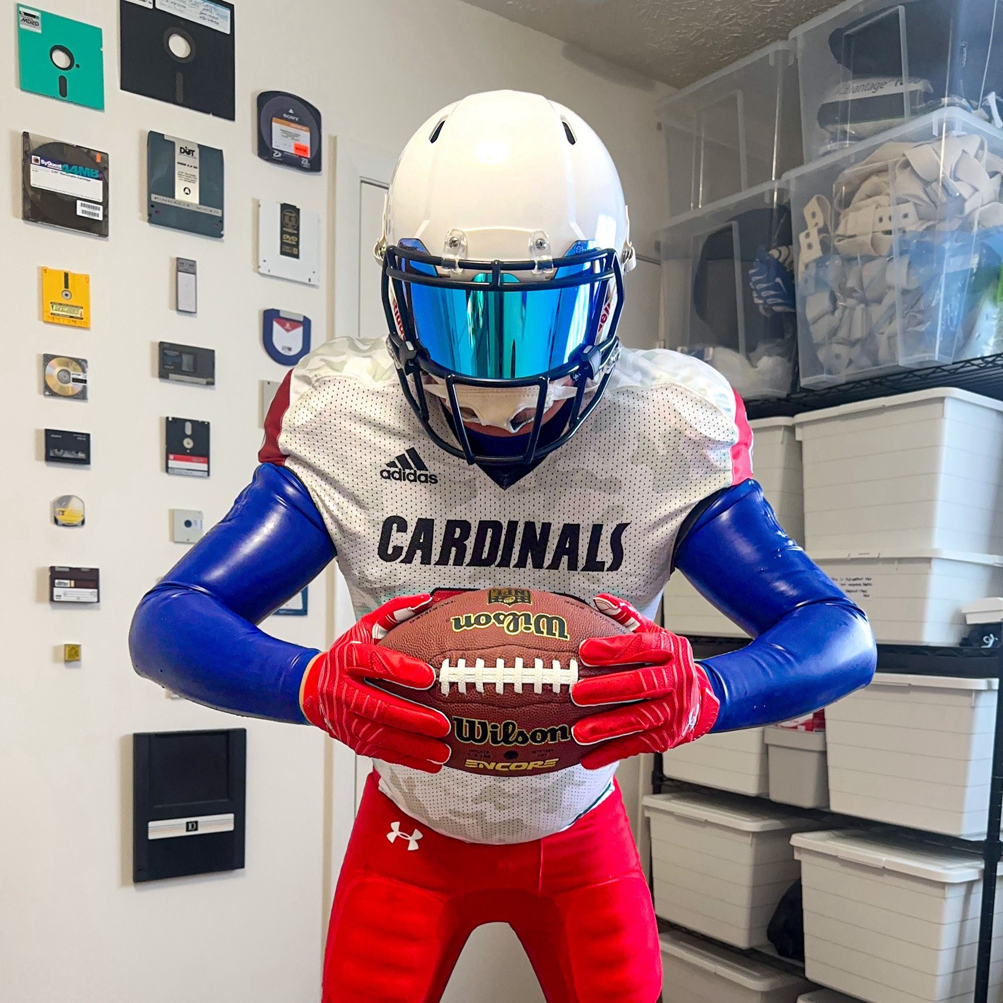 Man in blue rubber and white and red football gear, holding a football between hands