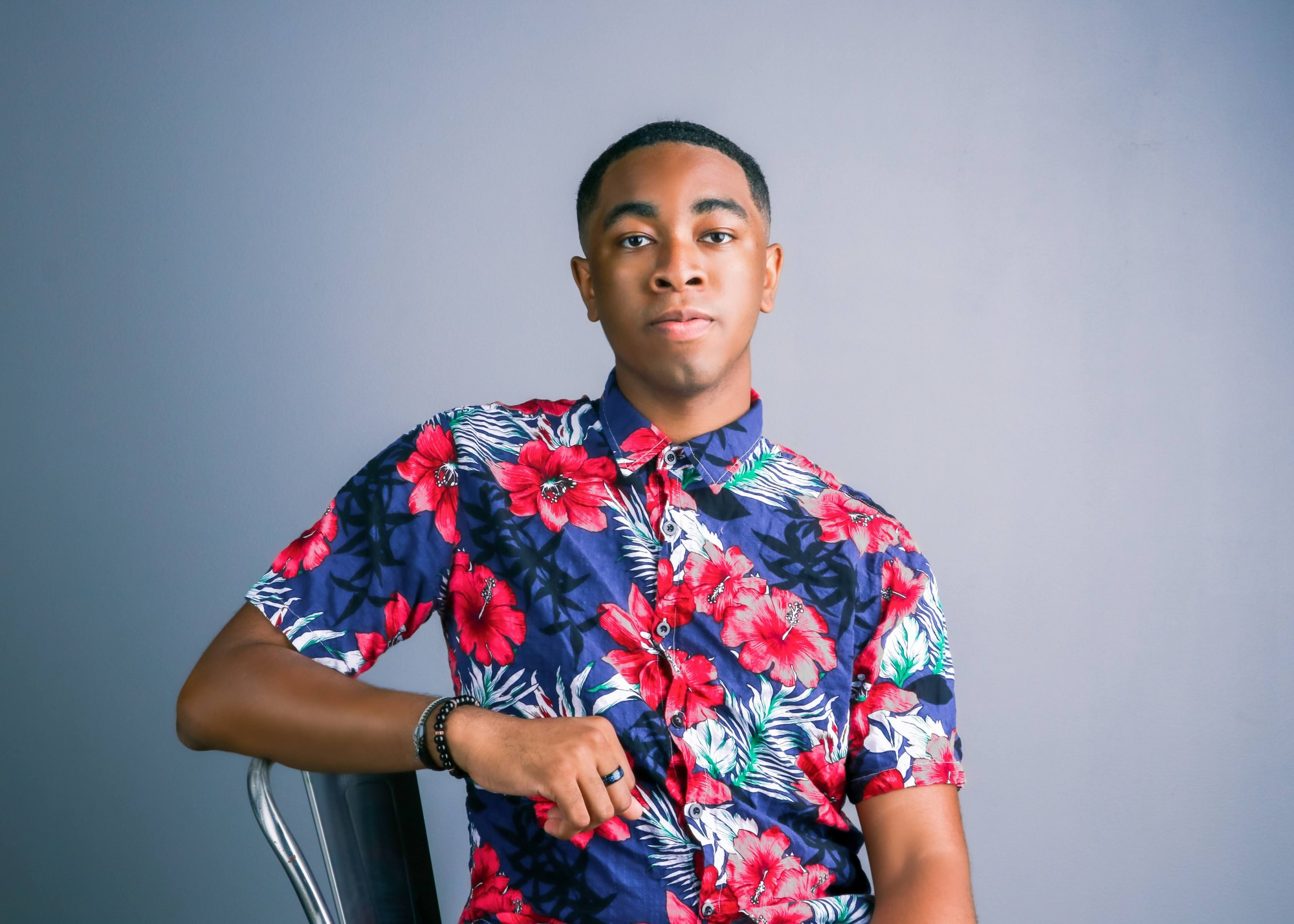 Napo leaning on a chair in a floral shirt