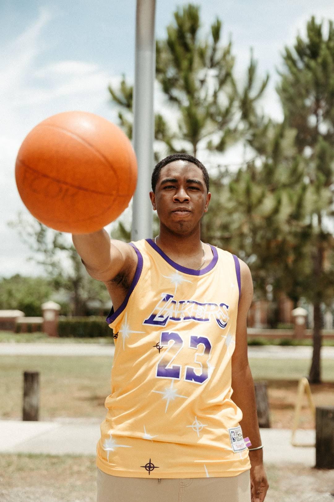 Napo standing with a basketball held out in his hands while wearing a LeBron Lakers jersey