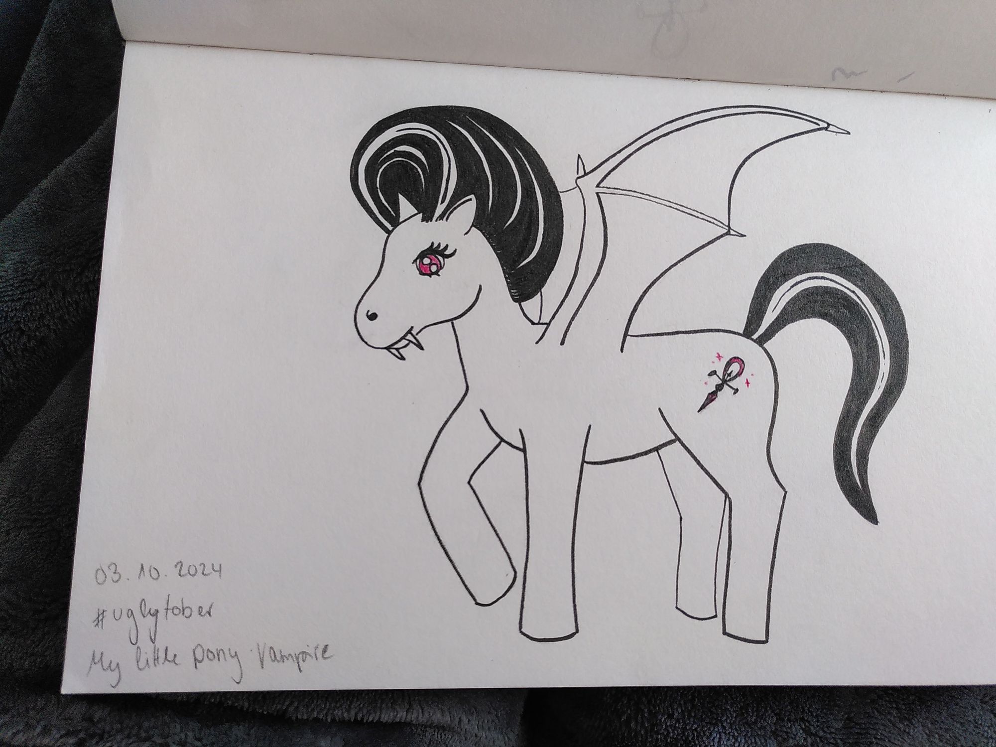 Sketchbook page with a drawing made with a black pen brush of a pony with fangs and bat wings. It has a black mane and a black tail with a white strand. On the flank there is an ankh symbol with some red details. The eyes of the pony are red too. 