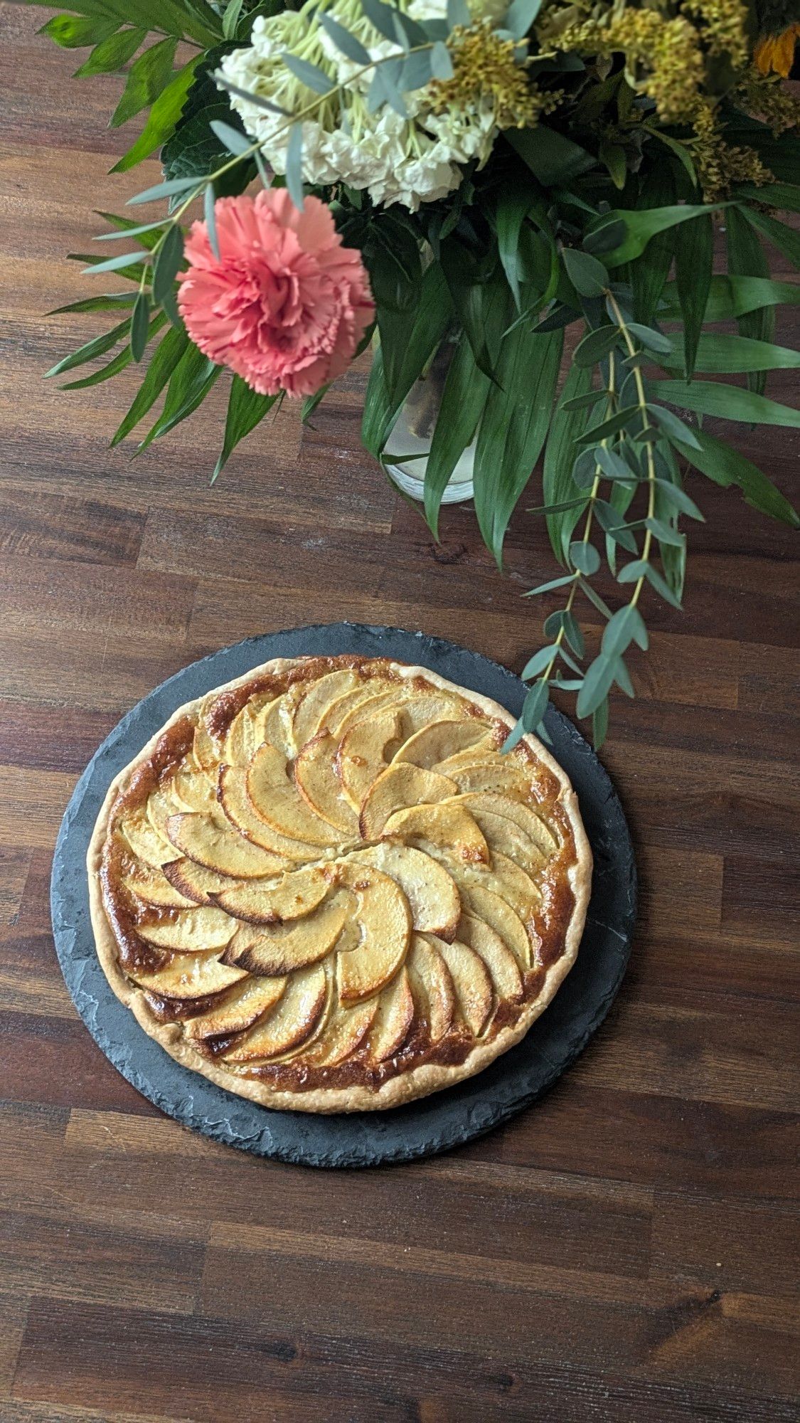 Tarte aux pommes et bouquet de fleurs.