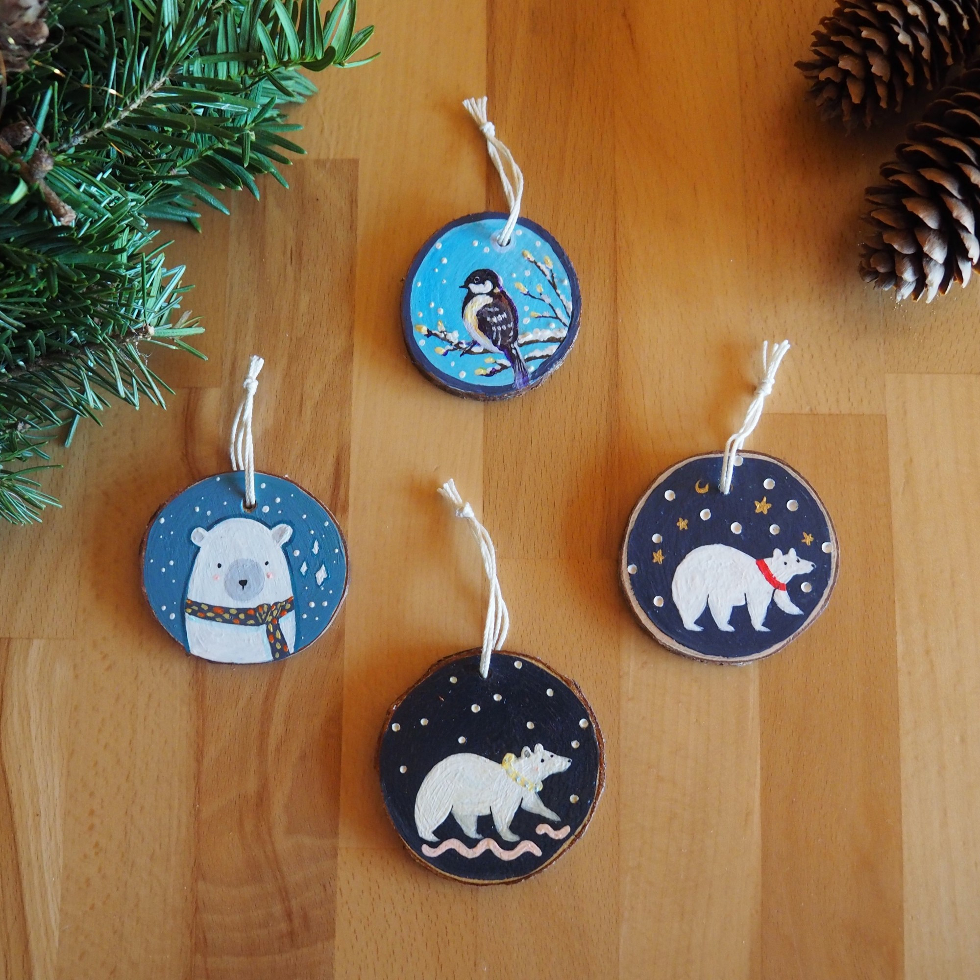 Four wood slices with three paintings of white bears and a bird.