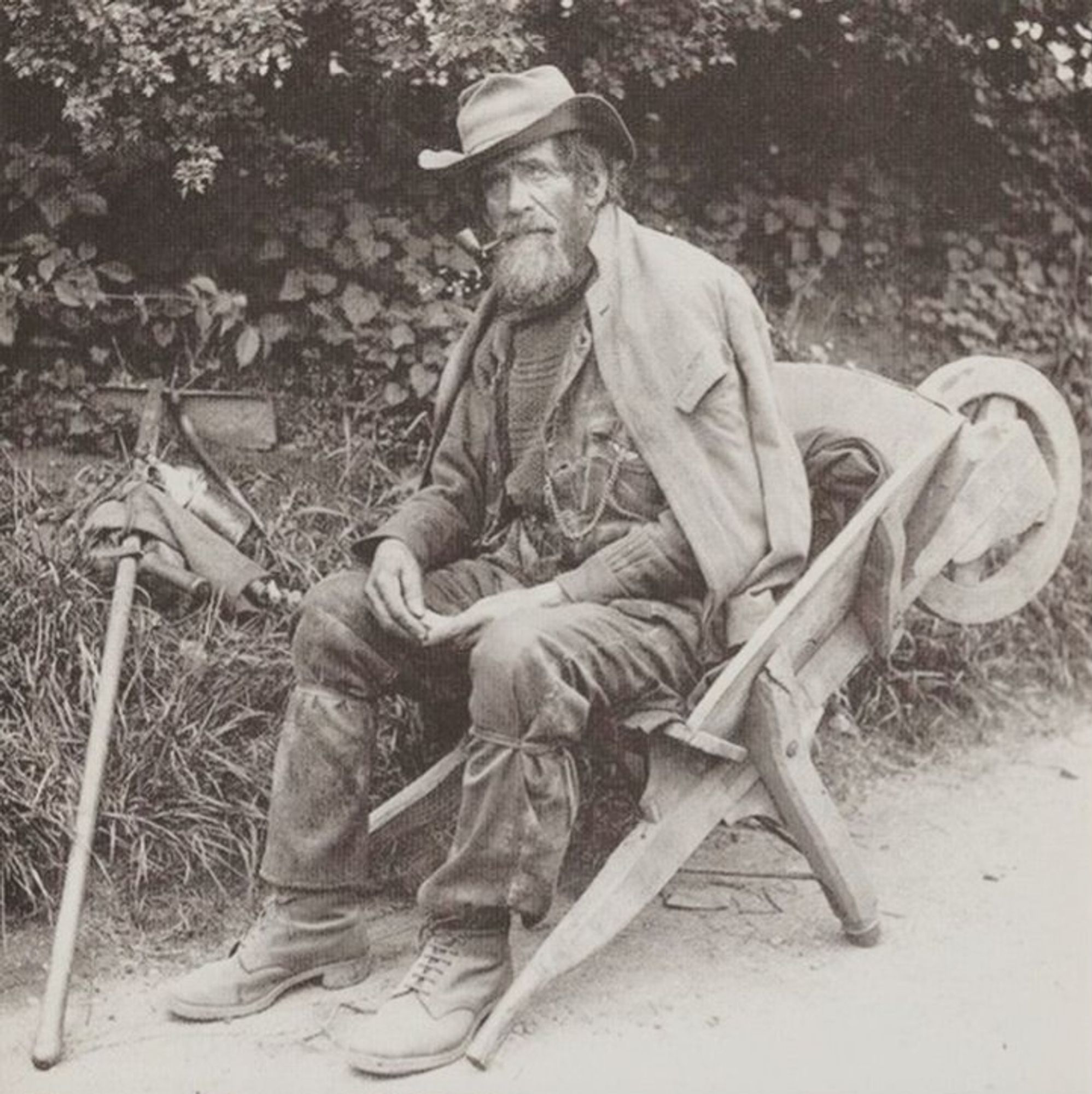 A photograph of an Edwardian working gardener using a wheelbarrow as a chair.