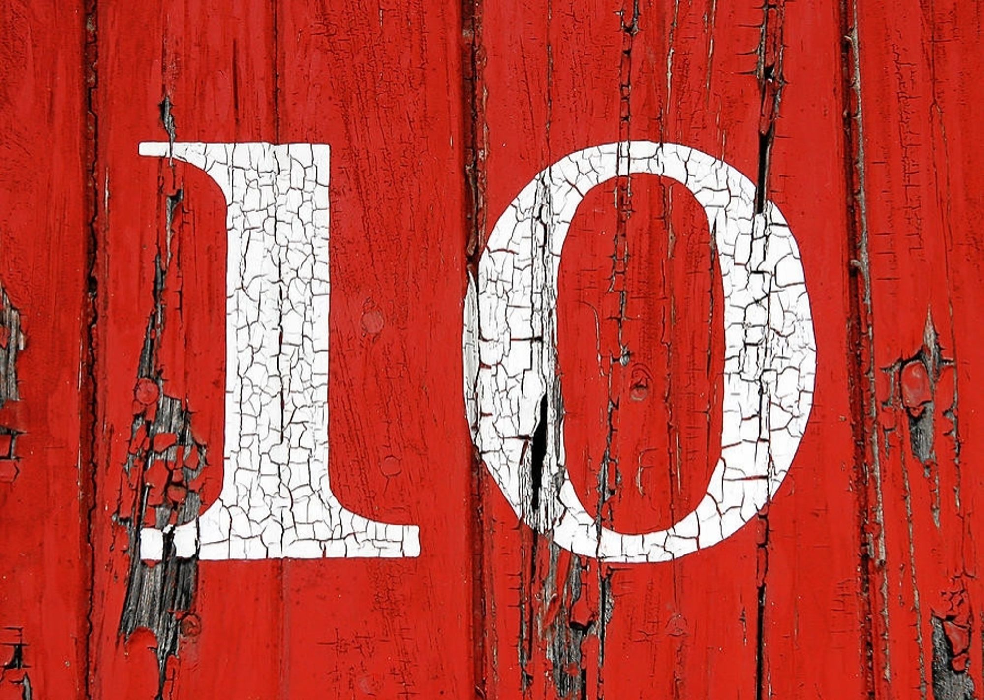 The number ten is painted in white on an old red door.