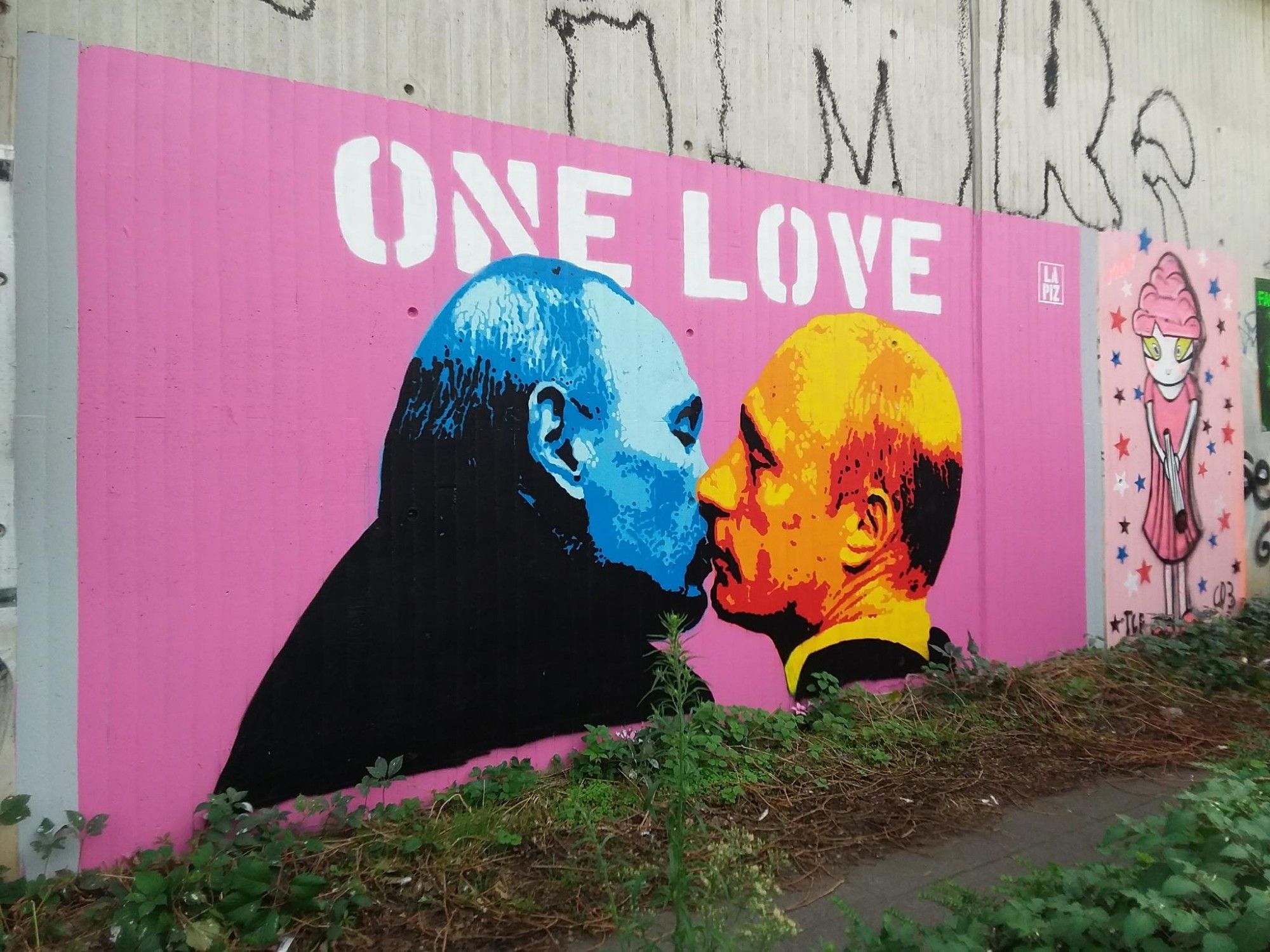 Ein Foto eines Grafitto auf dem Putin sich selber küsst, das mit One Love betitelt ist.