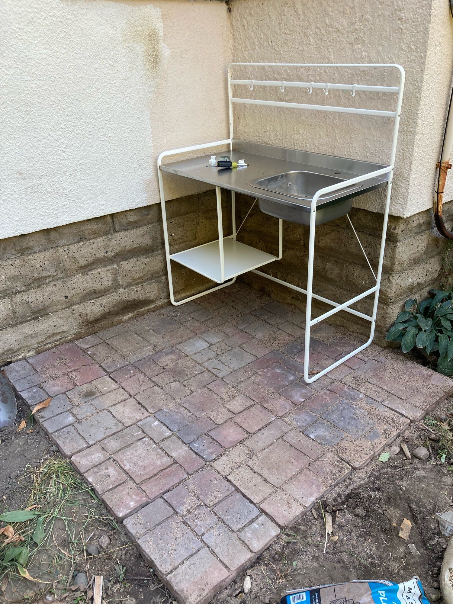 Same corner, but now there are patio pavers in place and a little sink counter thing from IKEA. The wall of the house is two different colors.