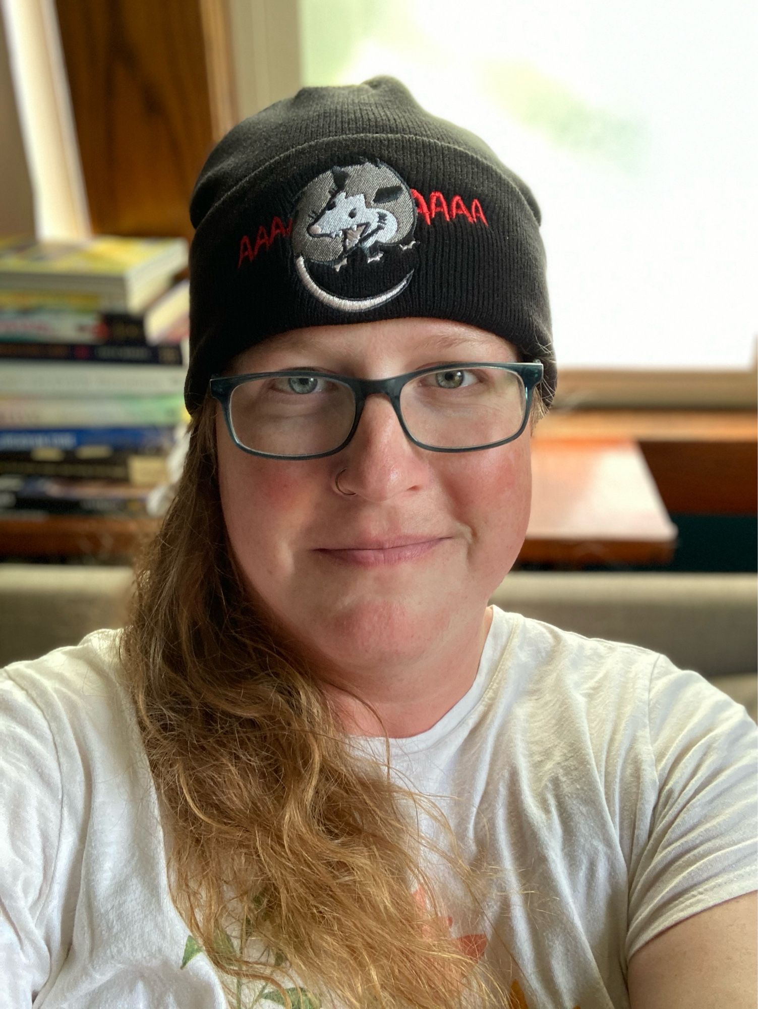 Ellie is wearing a black beanie with the “scream at own ass” possum embroidered on it.