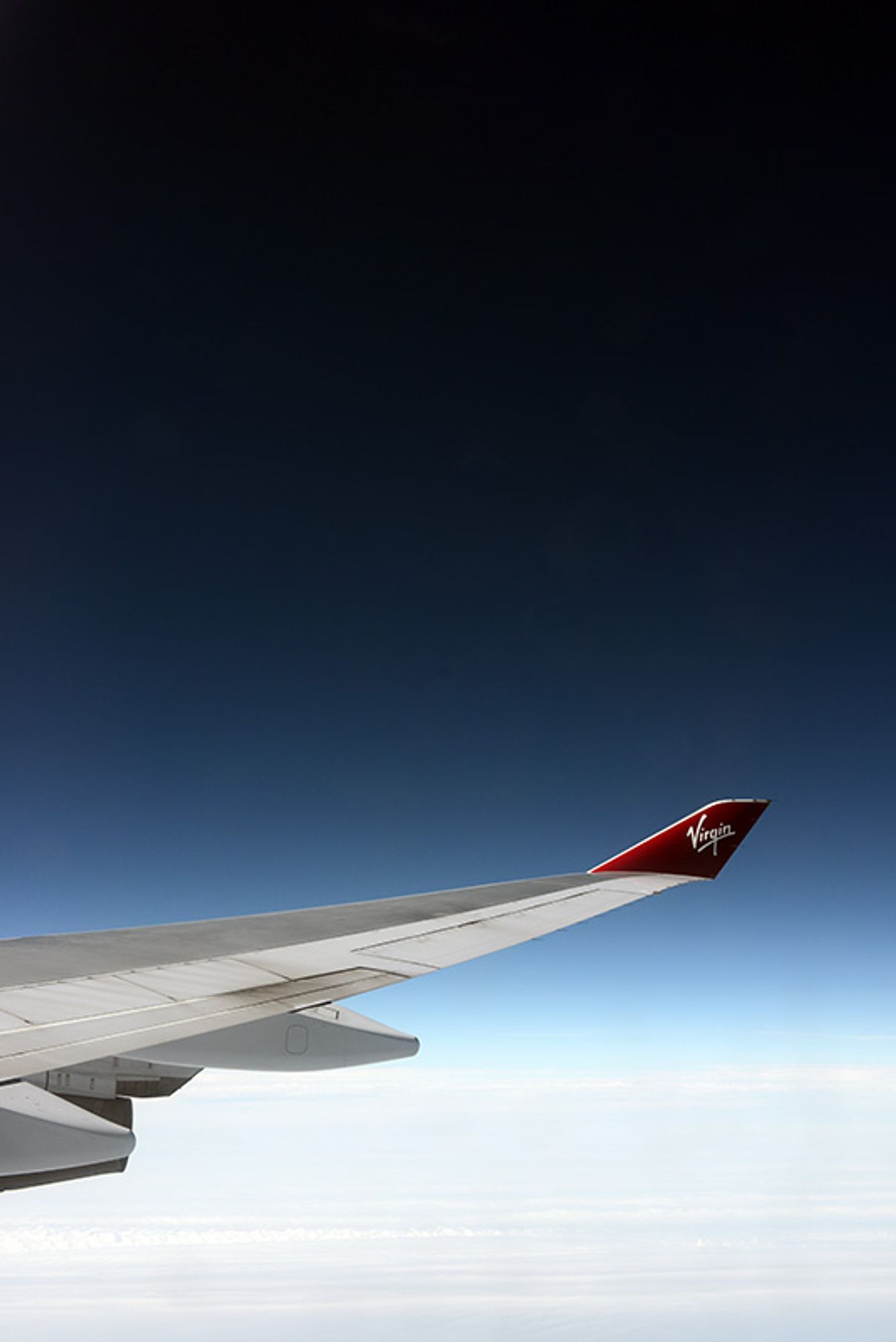 Starboard wing of a Boeing 747 at high altitude over the North Atlantic, with the sky deepening in colour as the atmosphere thins towards space...