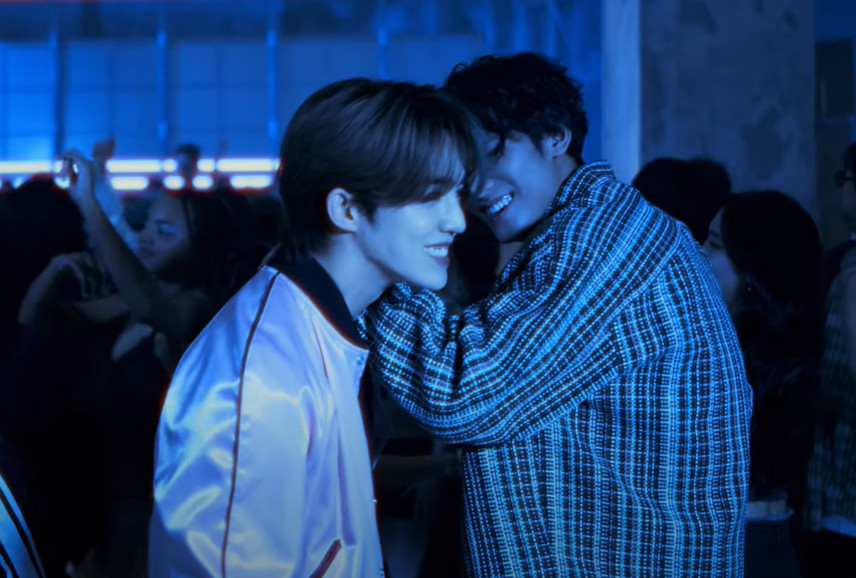 screenshot from the 'eyes on you' mv by kpop boy group seventeen, mingyu and seungcheol (scoups) laughing together in a club, mingyu's hand on seungcheol's shoulder