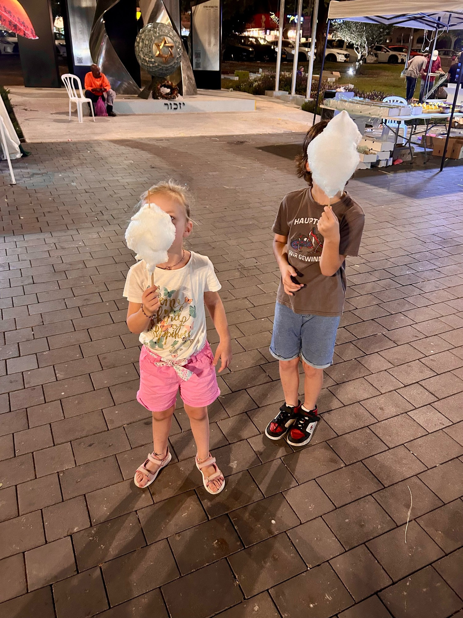 Zwei Kinder mit Zuckerwatte vor dem Gesicht. 