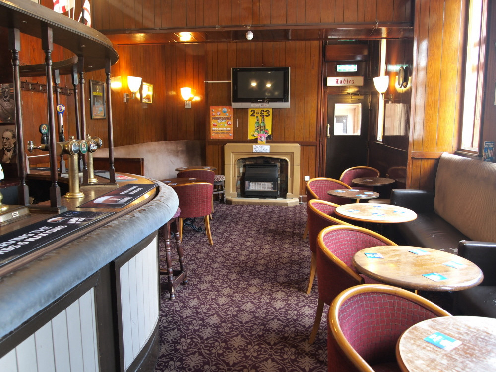 Lounge bar with original curved bar counter, stone fireplace, fixed bench seating, ‘Ladies’ sign and fittings circa. 1960’s.