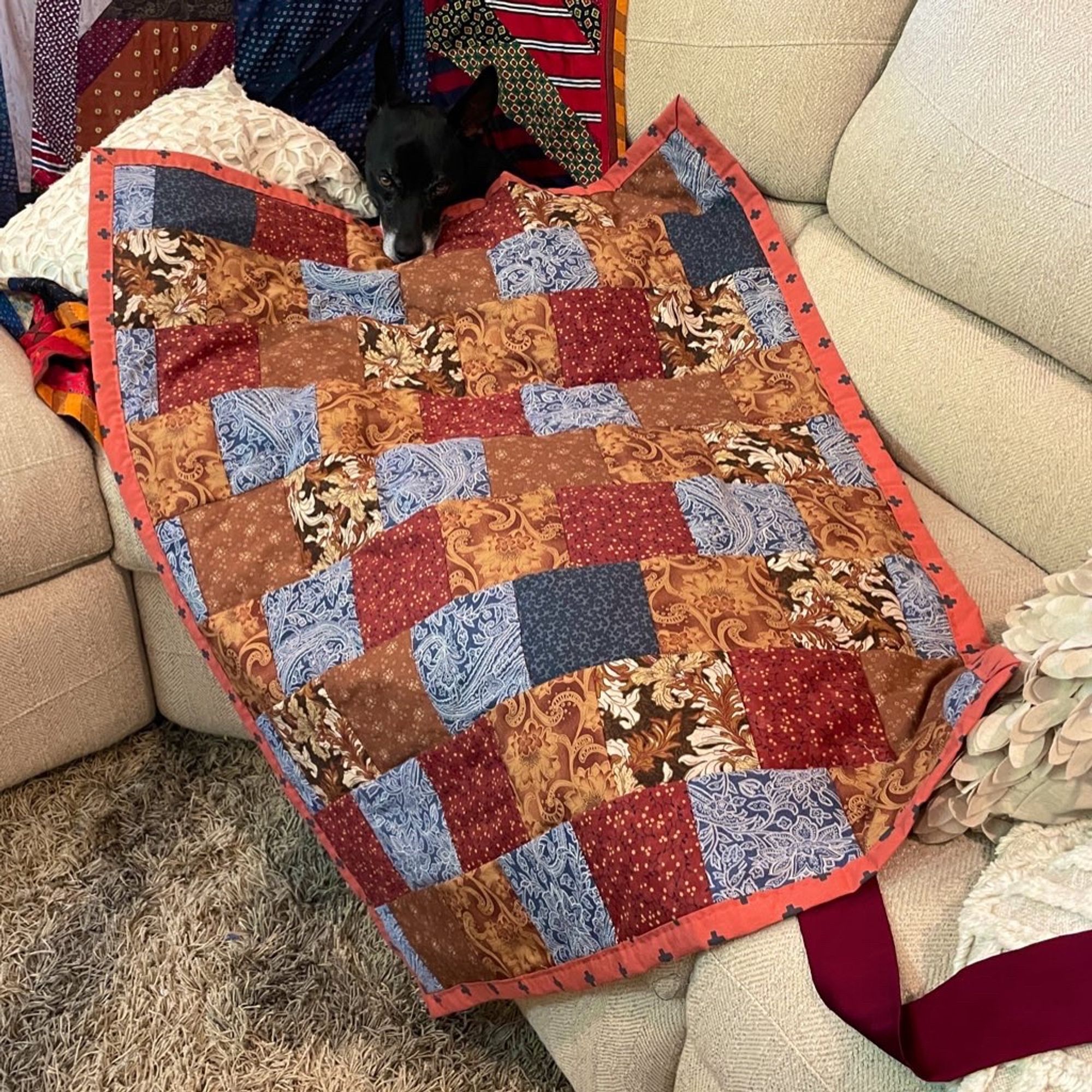 I threw my recently finished small quilt over my dog on the couch and she accepted it instantly. Mostly autumn type colors mixed with bluey grays.