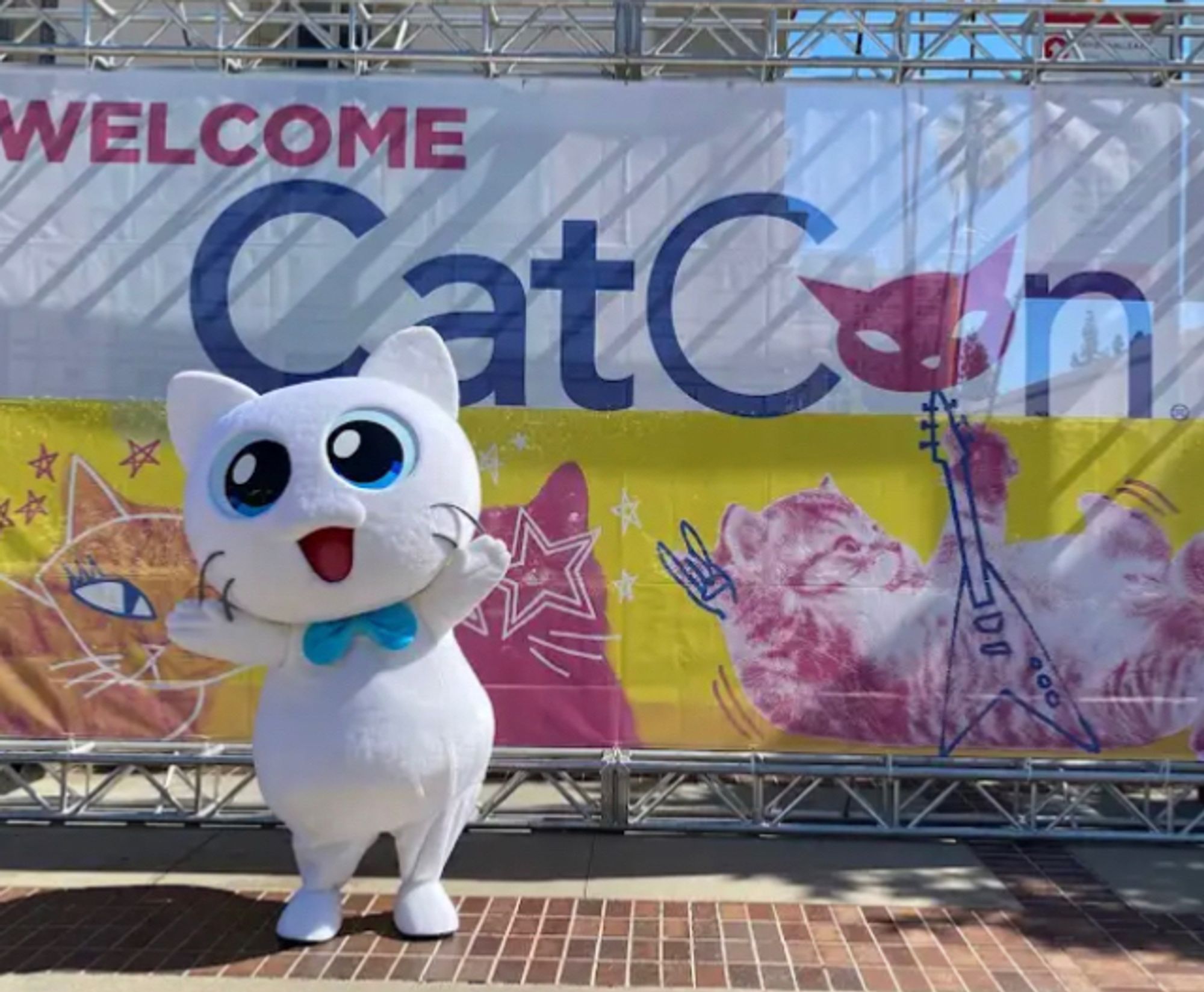 A big costume of a white cat with big blue eyes and a matching bow tie.