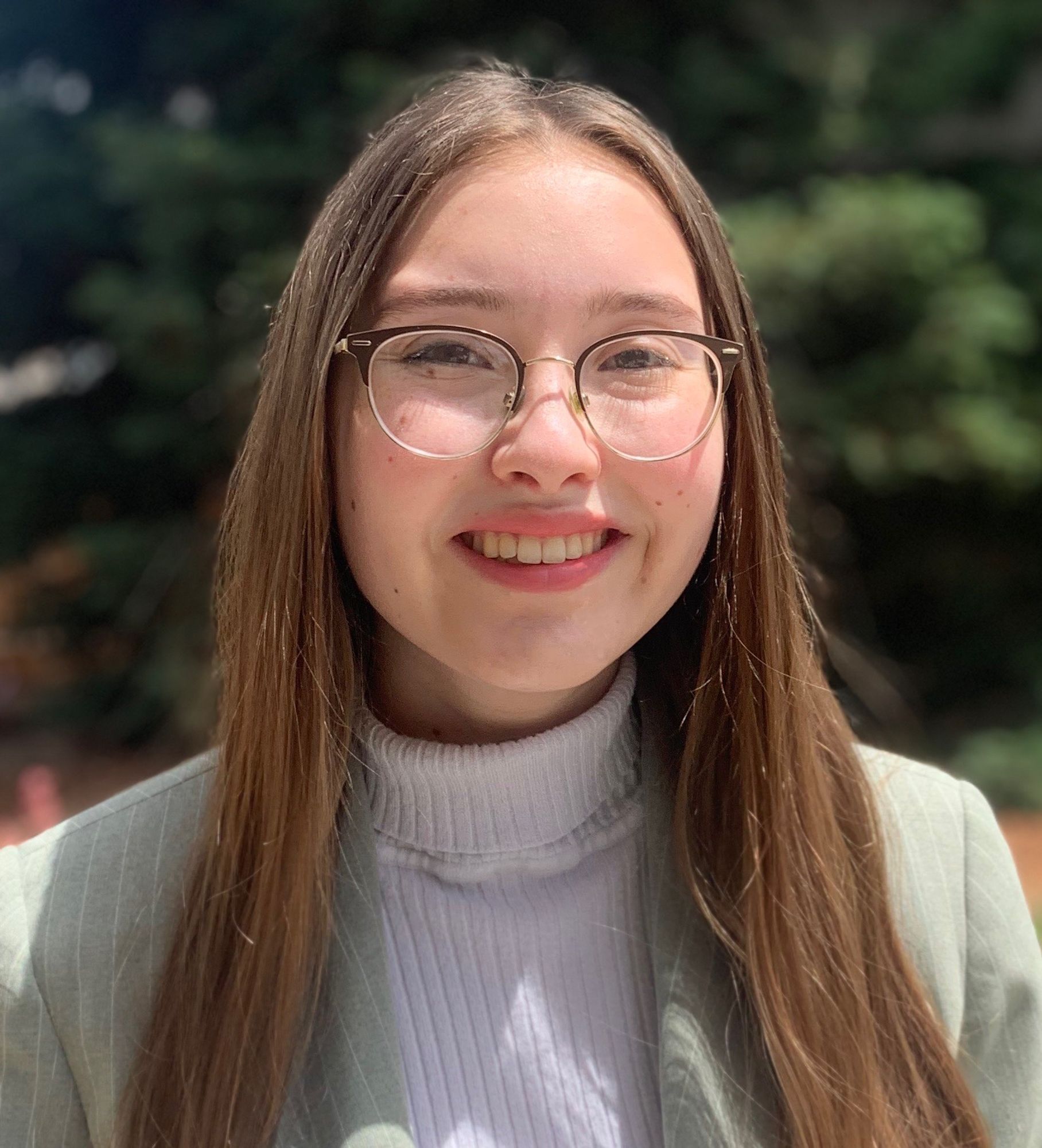 UCLA senior Rachel Simmons wears glasses, a lavender turtleneck, and a pinstriped gray jacket.