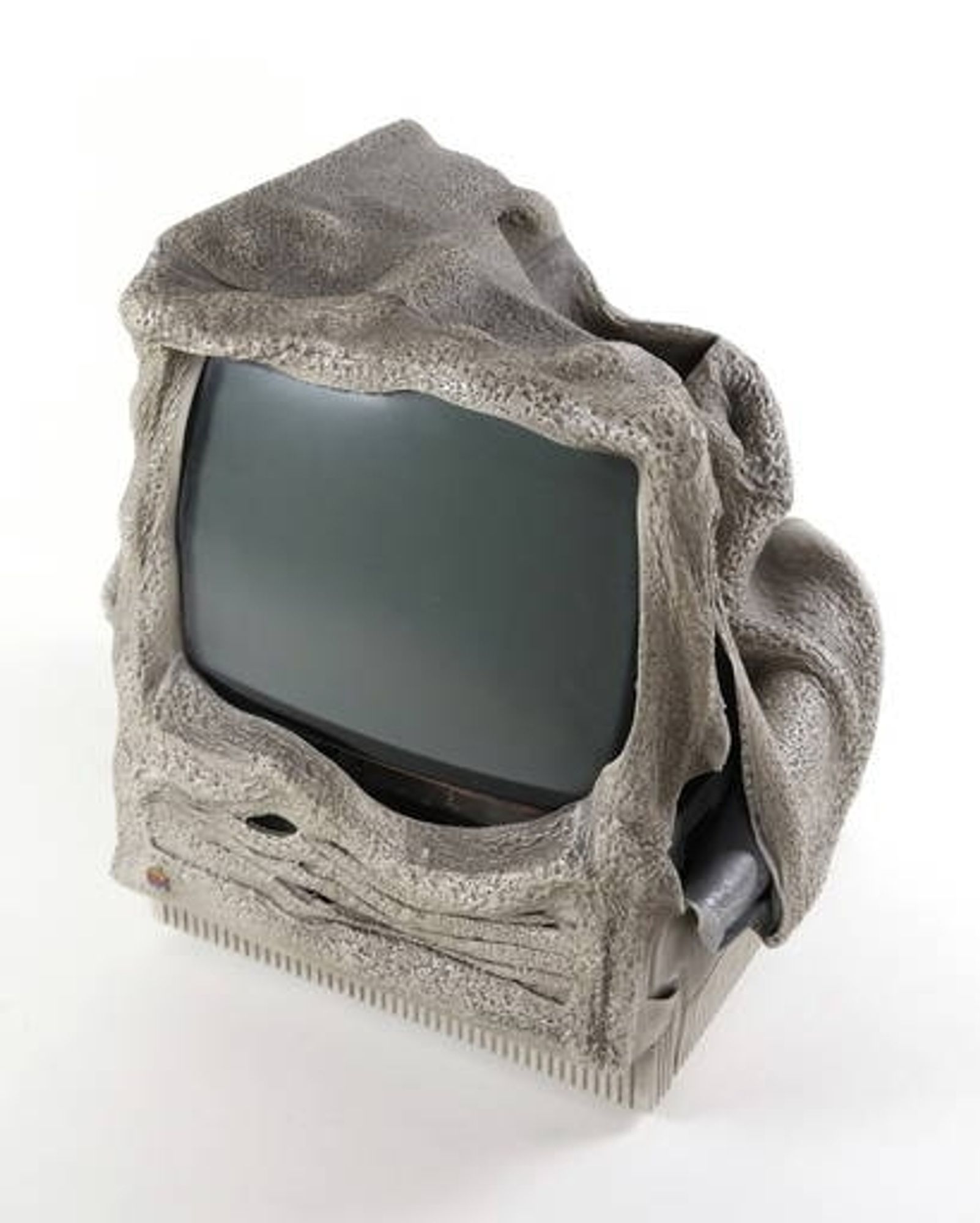 A vintage Macintosh computer (Classic or SE30 or similar form-factor) melted into a blob of plastic, yet still retains its fundamental shape. The plastic has only slight charring, making it appear as if it's textured and colored like grayish stone.