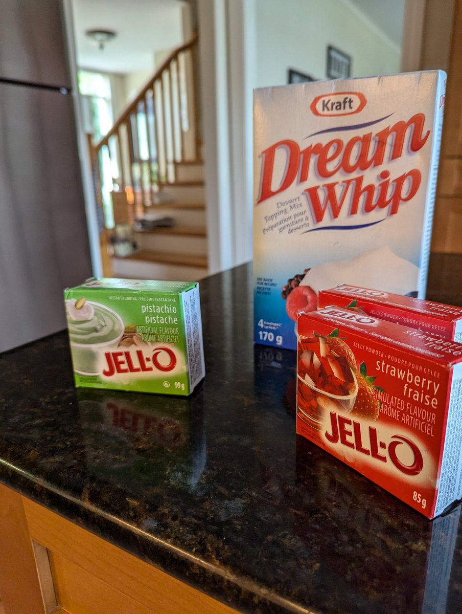 A package of pistachio pudding, two packs of strawberry jello, and a large box of Dream Whip