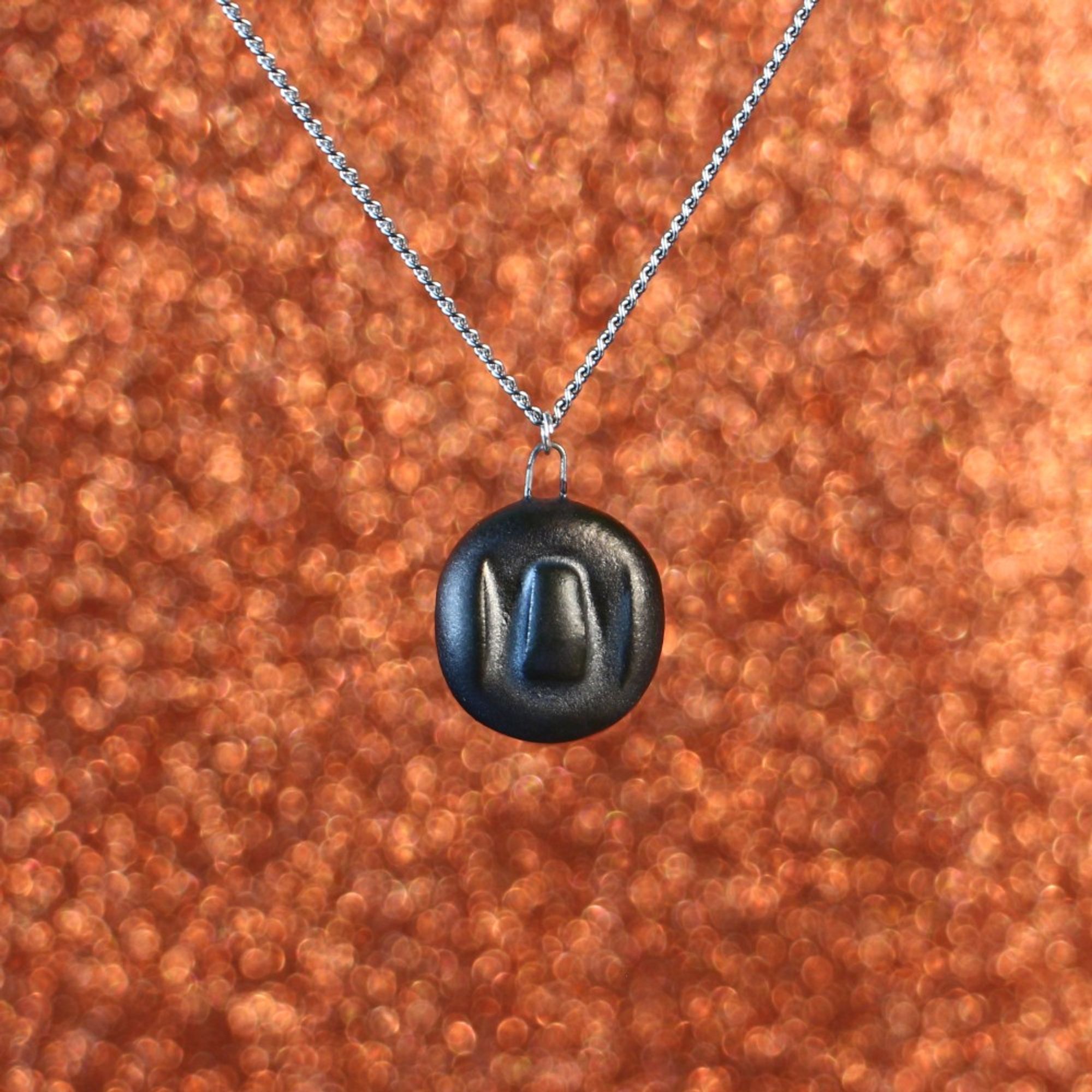 A matte metallic ceramic necklace with a pendant with a symbol that might mean something to someone, somewhere.