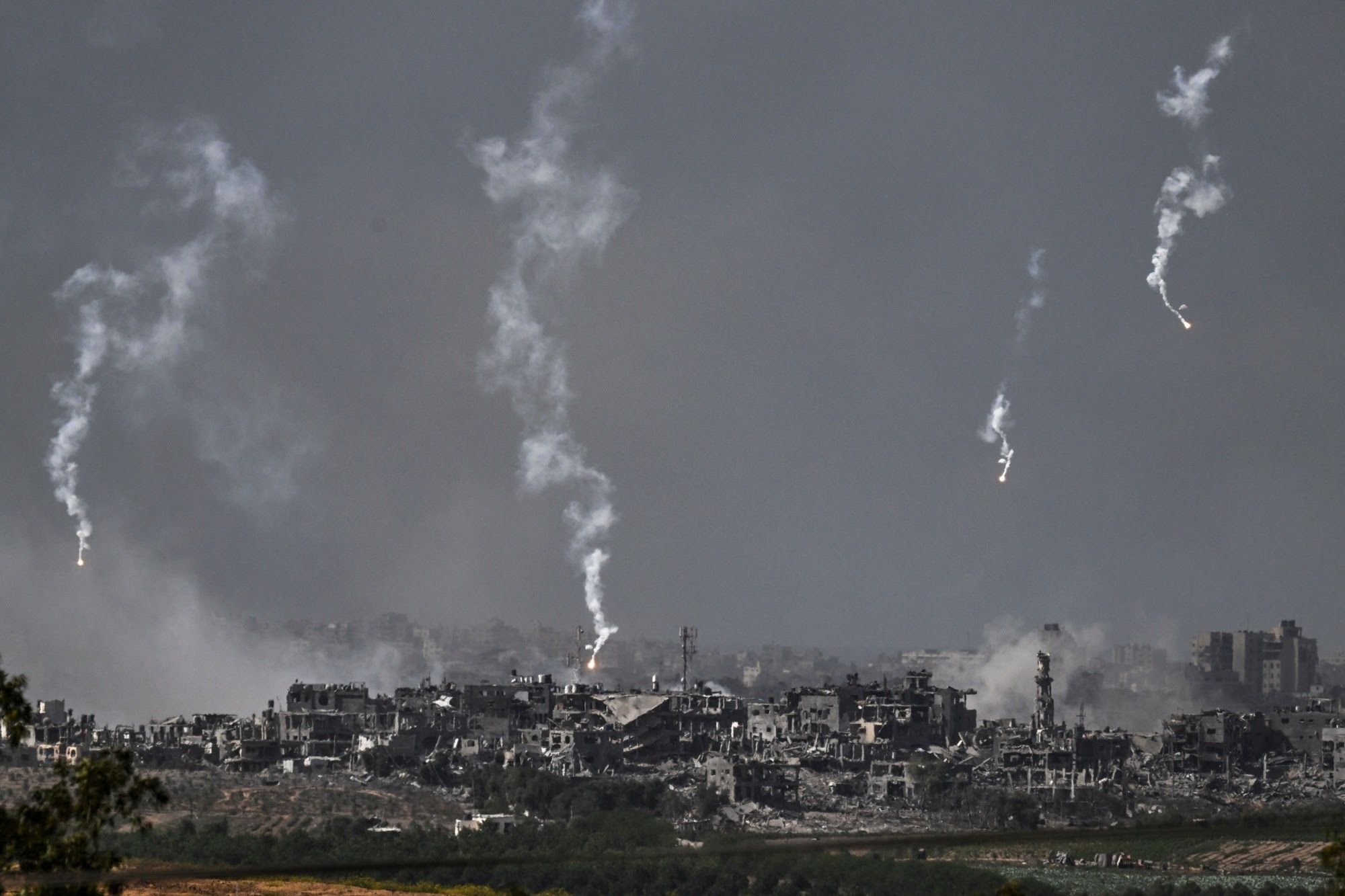 A grey wasteland, devastated Gaza buildings and the smokey trails of flares above them