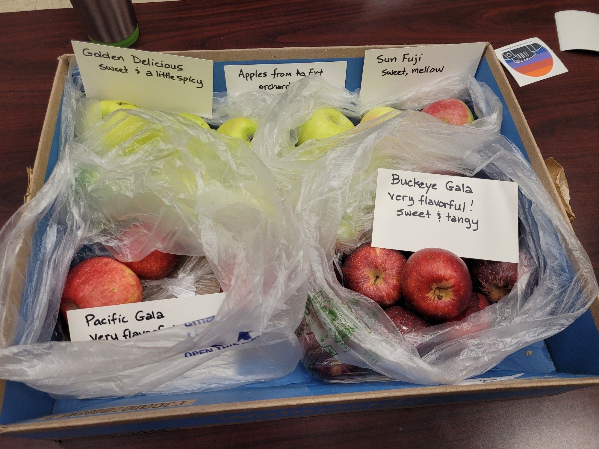 A box of green and red apples with each variety carefully labeled