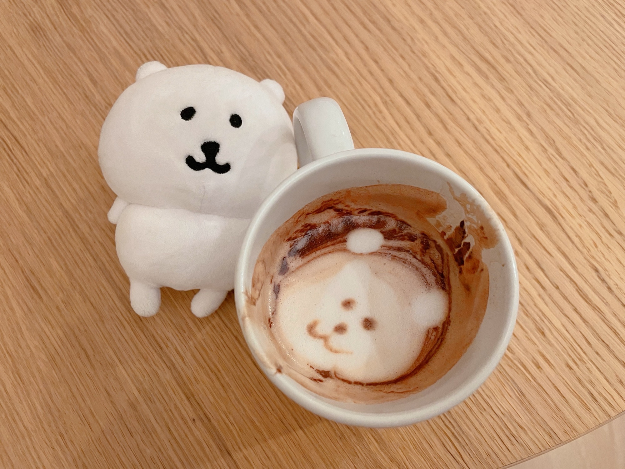 hot chocolate with a bear face in it next to a bear plush