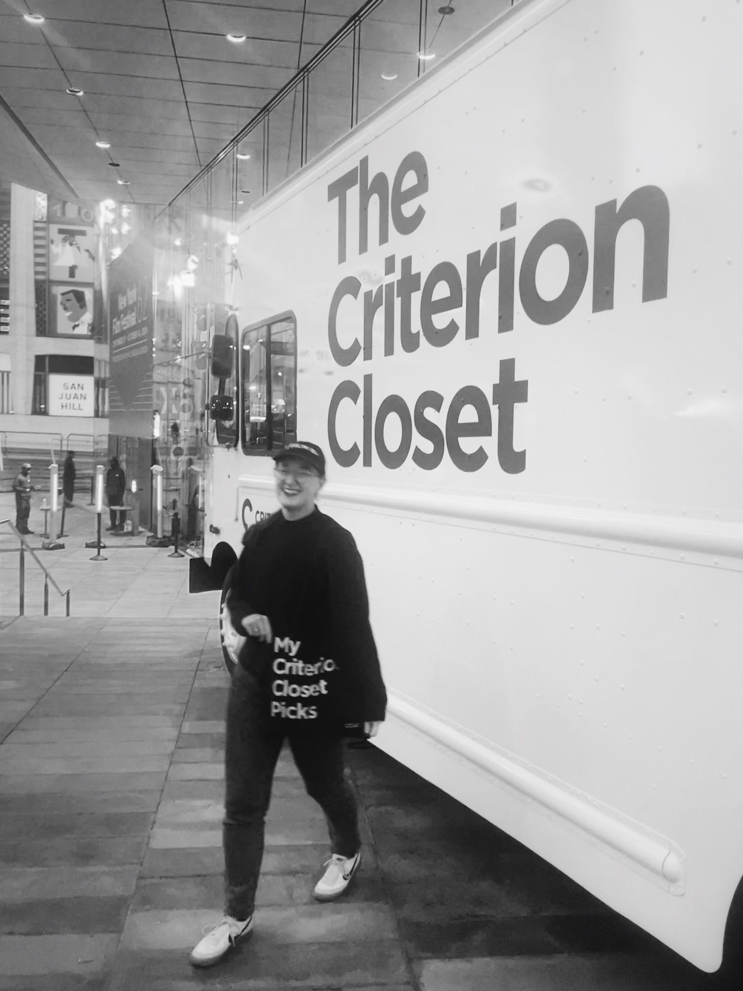 Me in front of the criterion van holding a tote with the text “My Criterion Closet Picks”