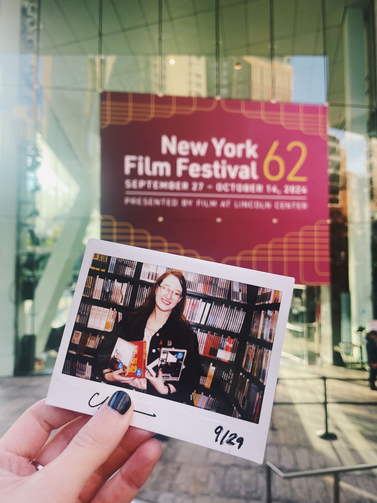 Holding up a Polaroid of me in the Criterion van closet in front of the NYFF62 sign