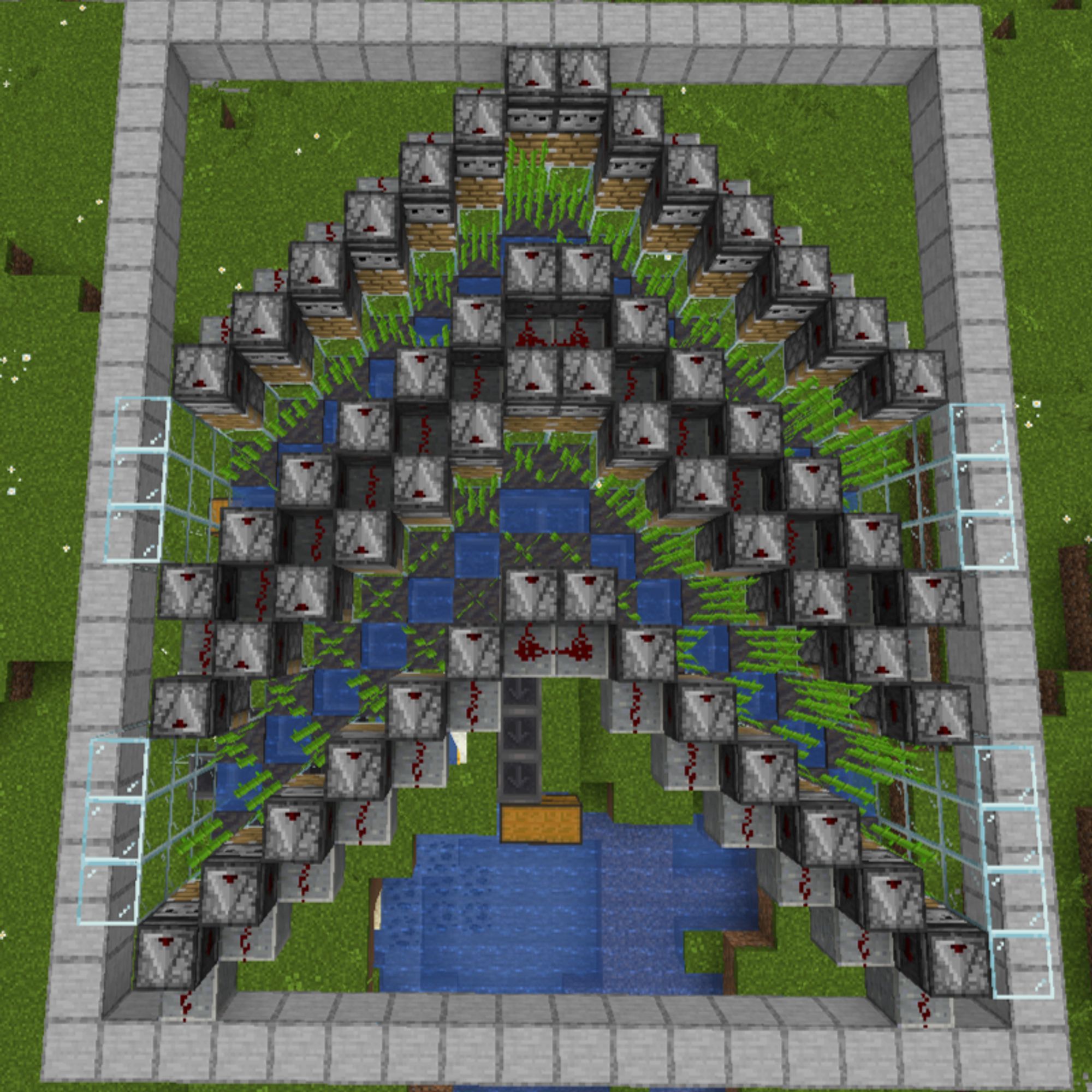 A chevron of gray blocks with splashes of a muddy gray and deep blues, with pops of dark green stalks in between. It's all on a background of green minecraft grass and boxed in by light gray blocks.