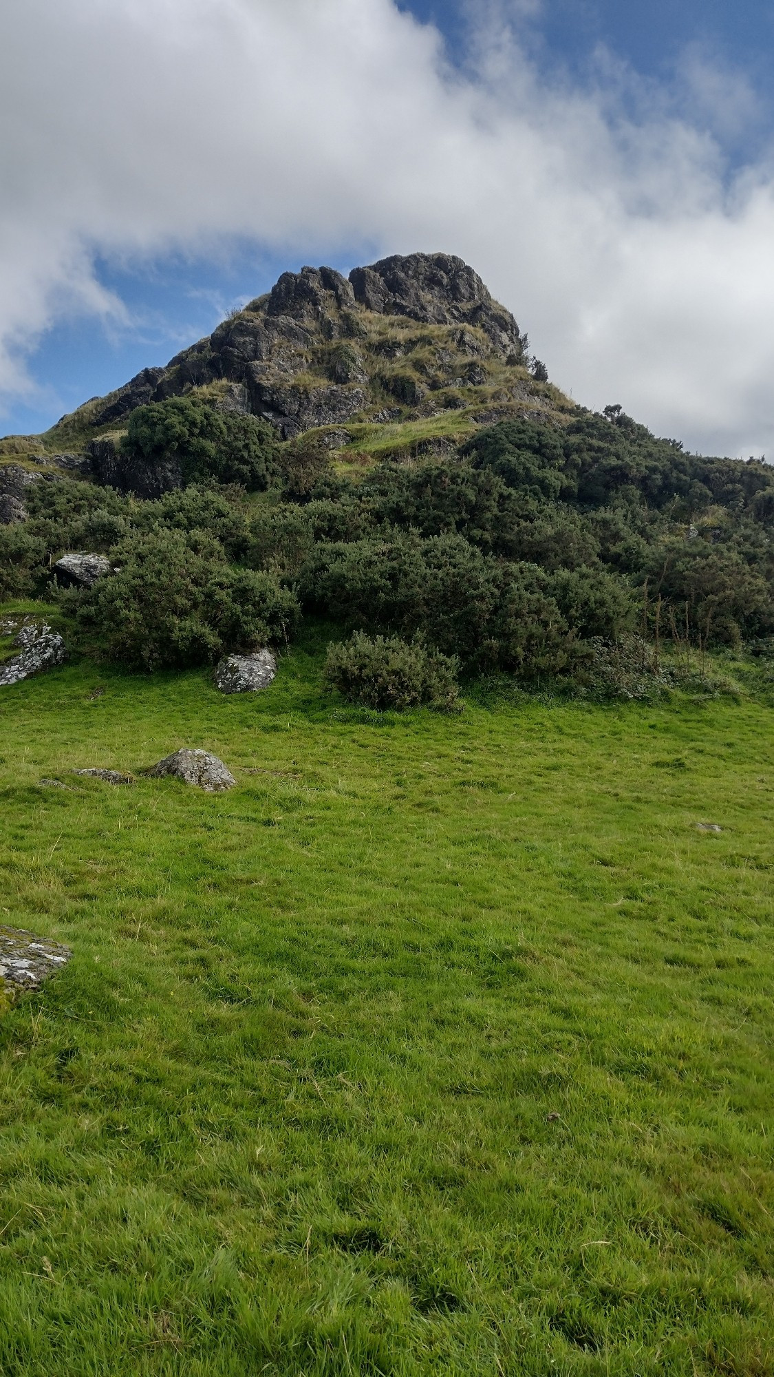 Image of basalt rock, once effusively erupted in a marine environment.  Now exposed as a hill surrounded by grass and moorland.