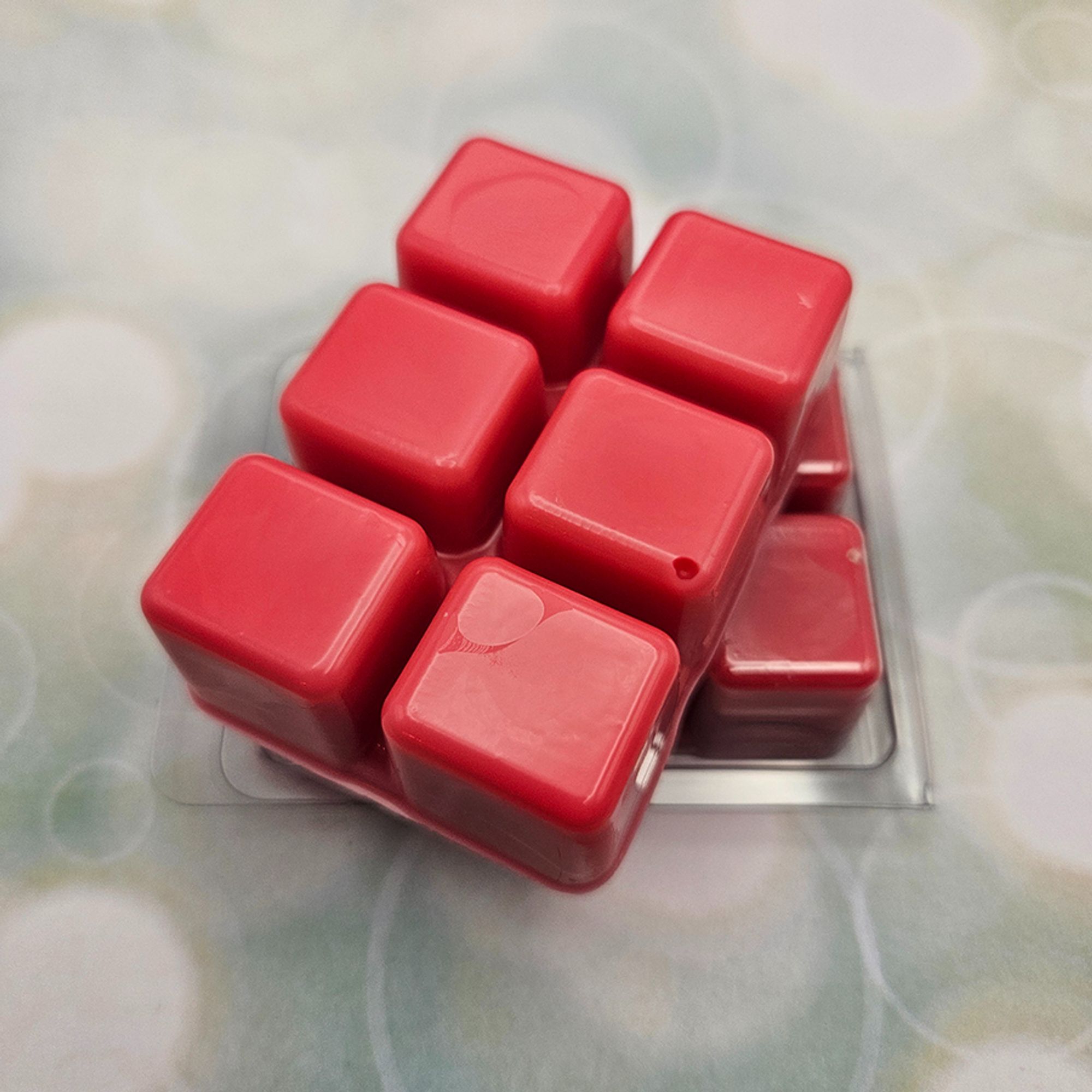 A set of wax melts out of a clamshell on a light green background with circles. The pictured scent is Fyrefly Type-IV - Complete Combustion: Firefly.