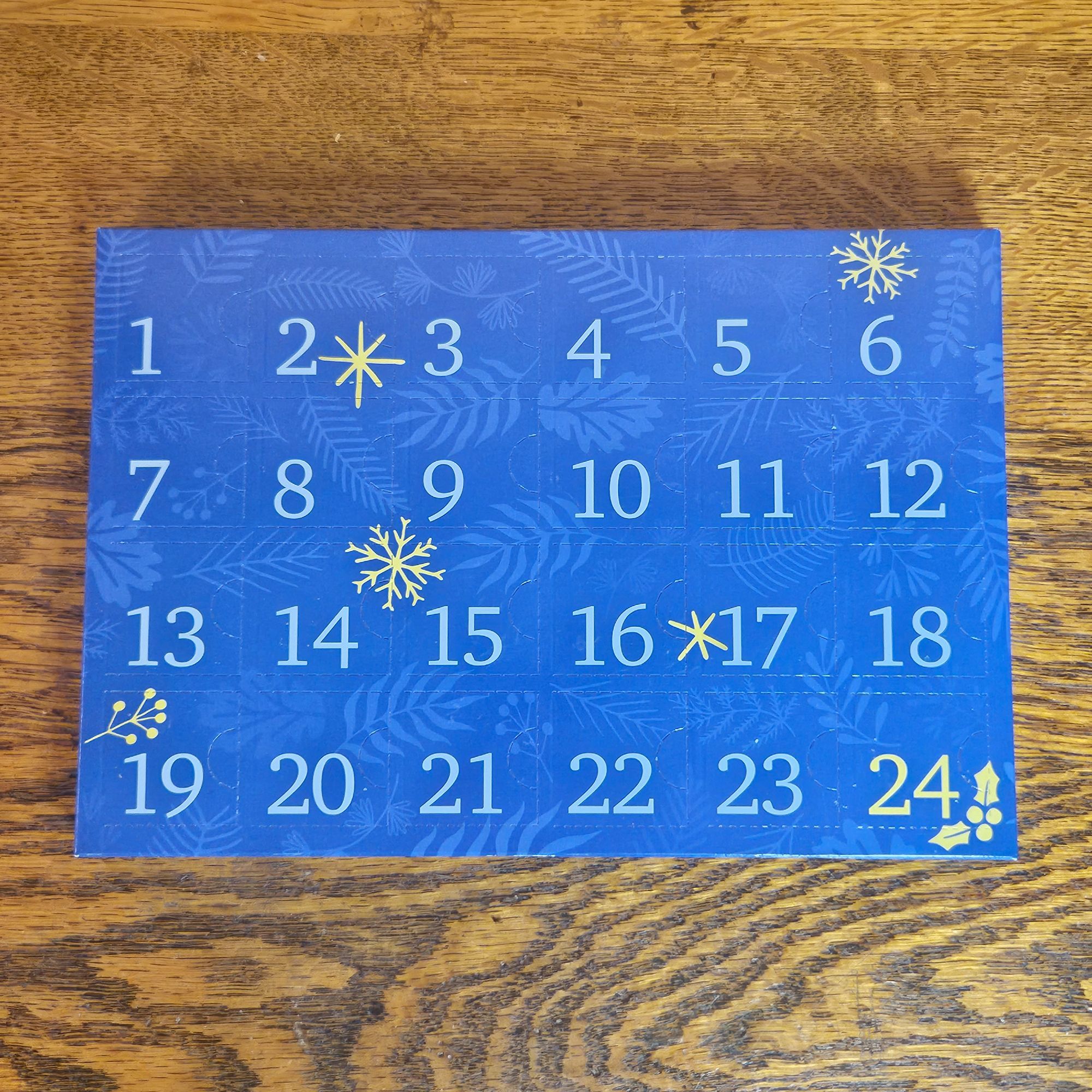 A blue advent calendar box with golden snowflakes on a wooden background.