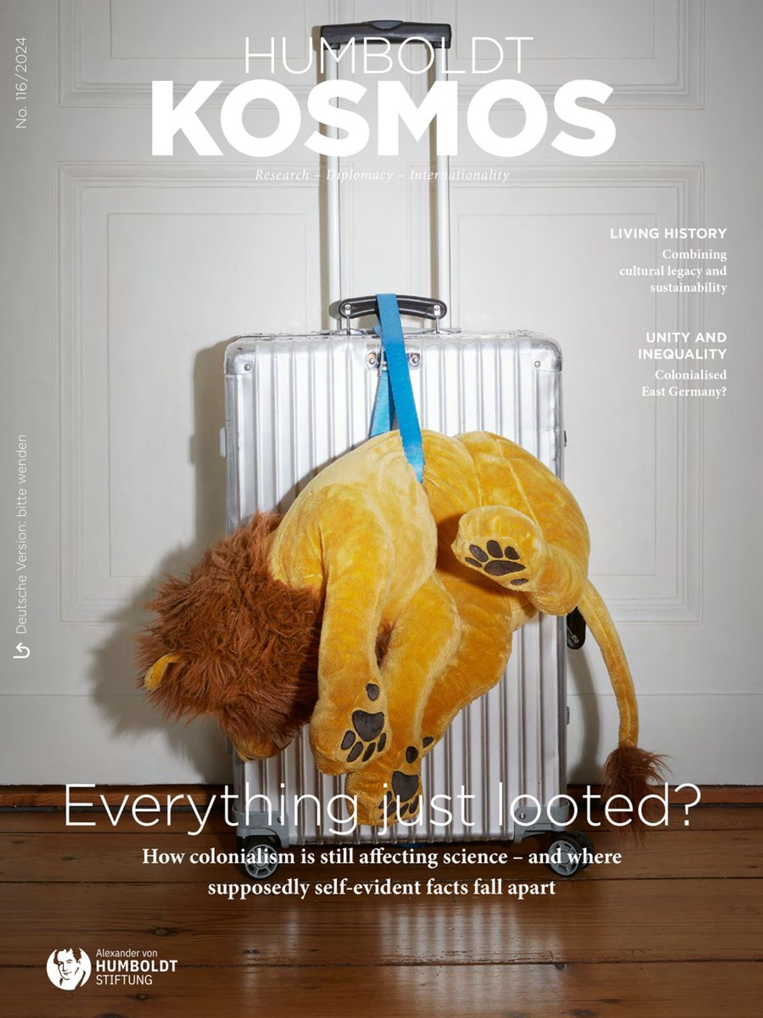 Cover of the new Humboldt Kosmos magazine. It shows a suitcase with a souvenir - a stuffed lion - hanging from it. Text: Everything just looted? How colonilism is still affecting science - and where supposedly sef-evident facts fall apart.