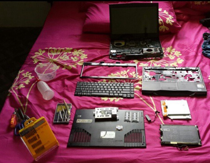 A disassembled laptop on a bed