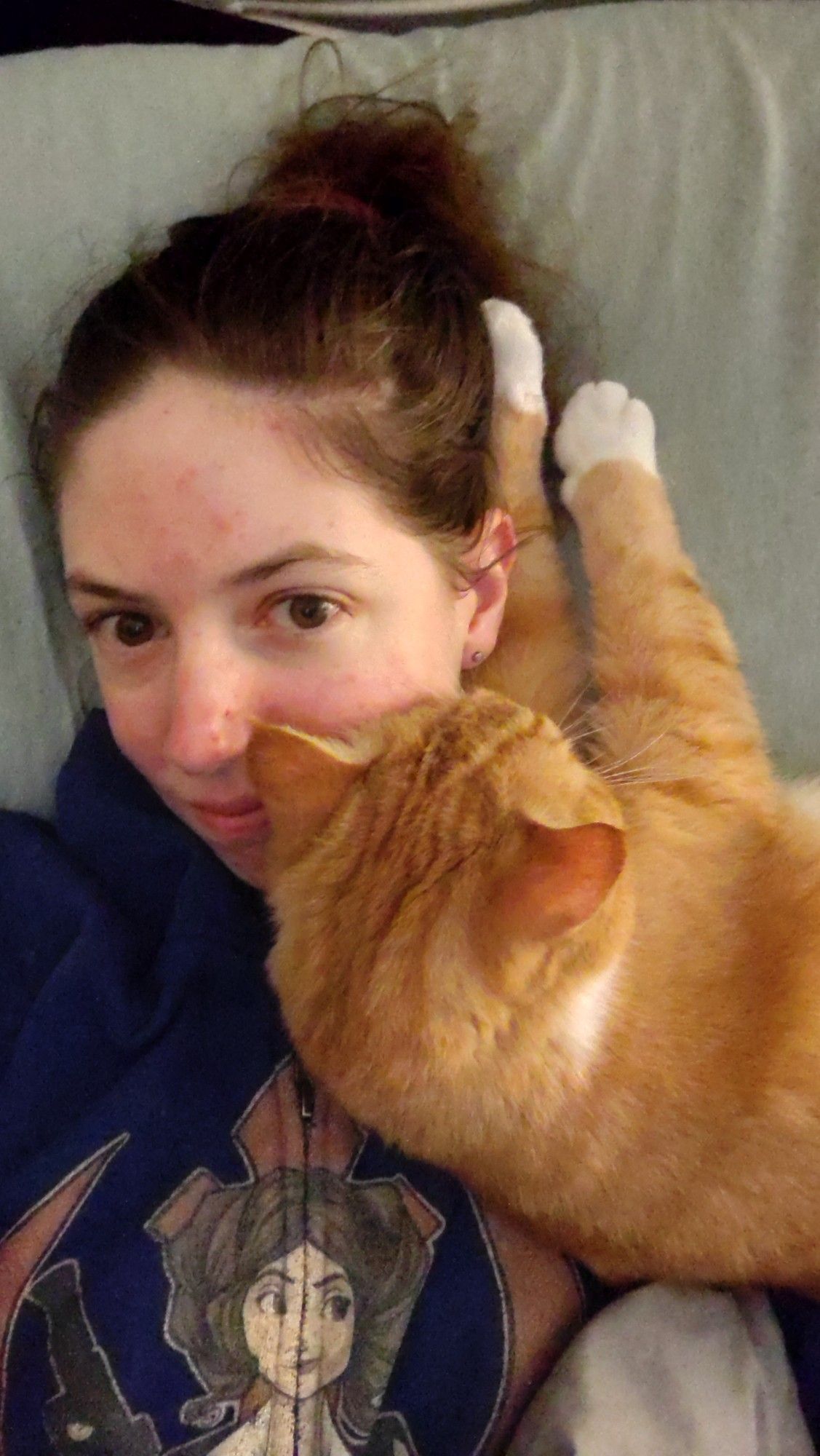 My cat, Stormy, an orange tabby, laying across my chest and smoothing his face into mine while we cuddle in bed