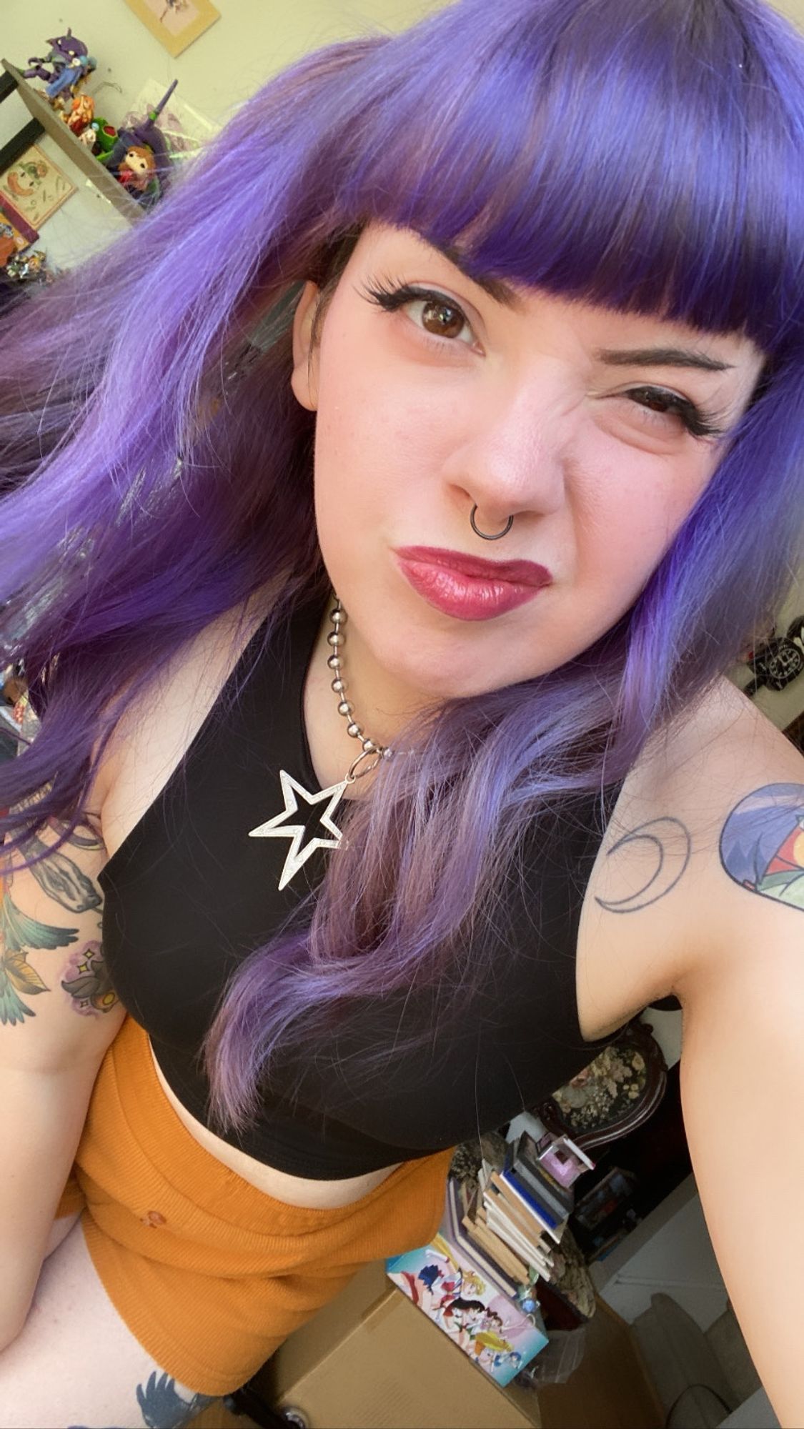 purple hair girl bends down and pulls a kind of silly face while looking into camera