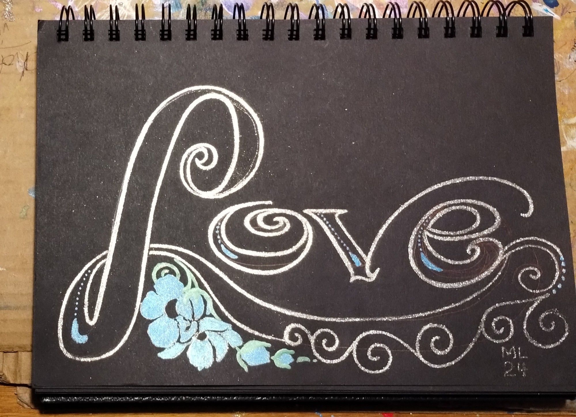 Continued doodle if the word 'Love'.
Metallic ink on black adding swirls and blue metallic flowers along tail of 'L'
ML
24