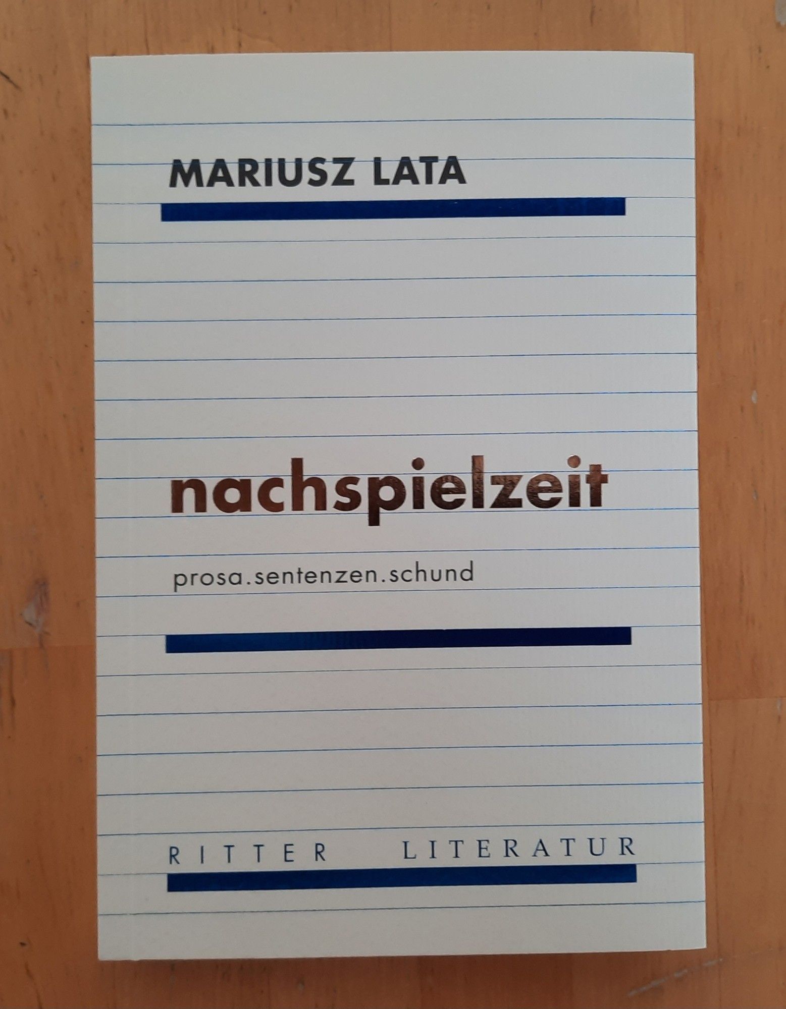 Titelseite eines Taschenbuchs, fein liniert wie ein Schreibheft. Oben beschriftet mit 'MARIUSZ LATA', in der Mitte mit ''nachspielzeit' darunter 'prosa.sentenzen.schund', unten mit 'RITTER  LITERATUR'.