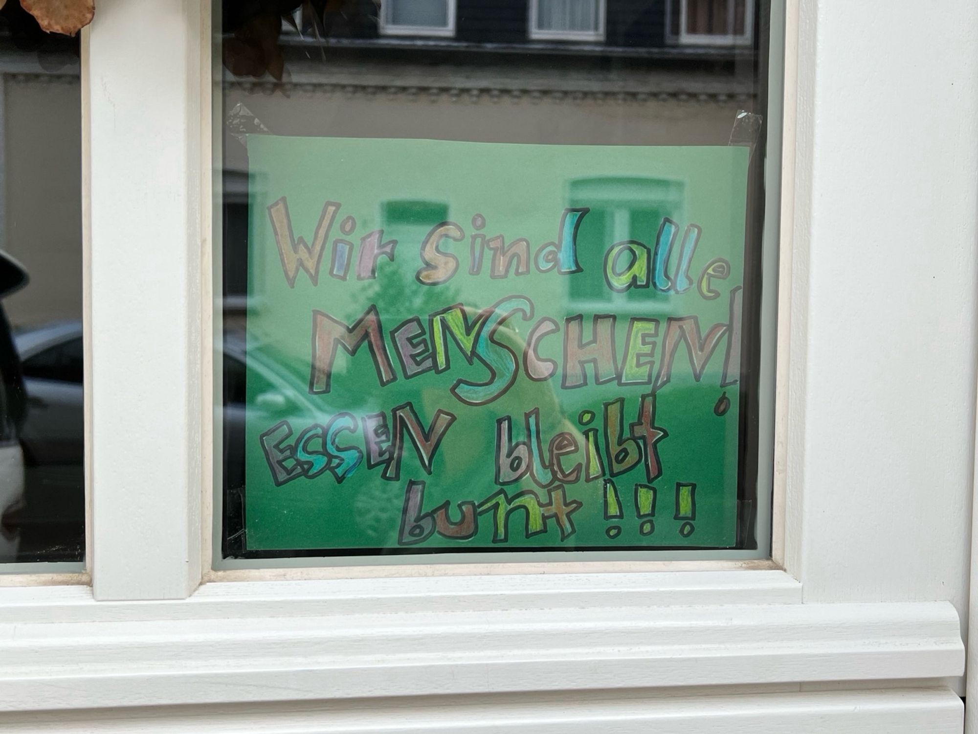 Grünes Fensterplakat „Wir sind alle Menschen! Essen bleibt bunt!“