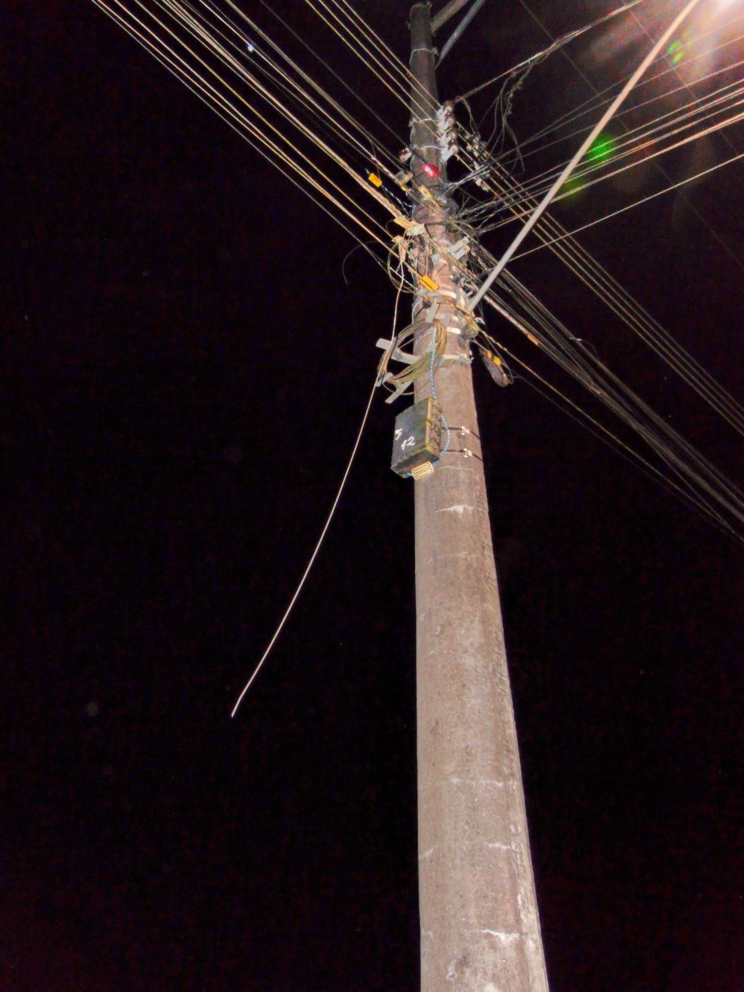 Foto de um poste de luz com um cabo de Fibra Óptica cortado.