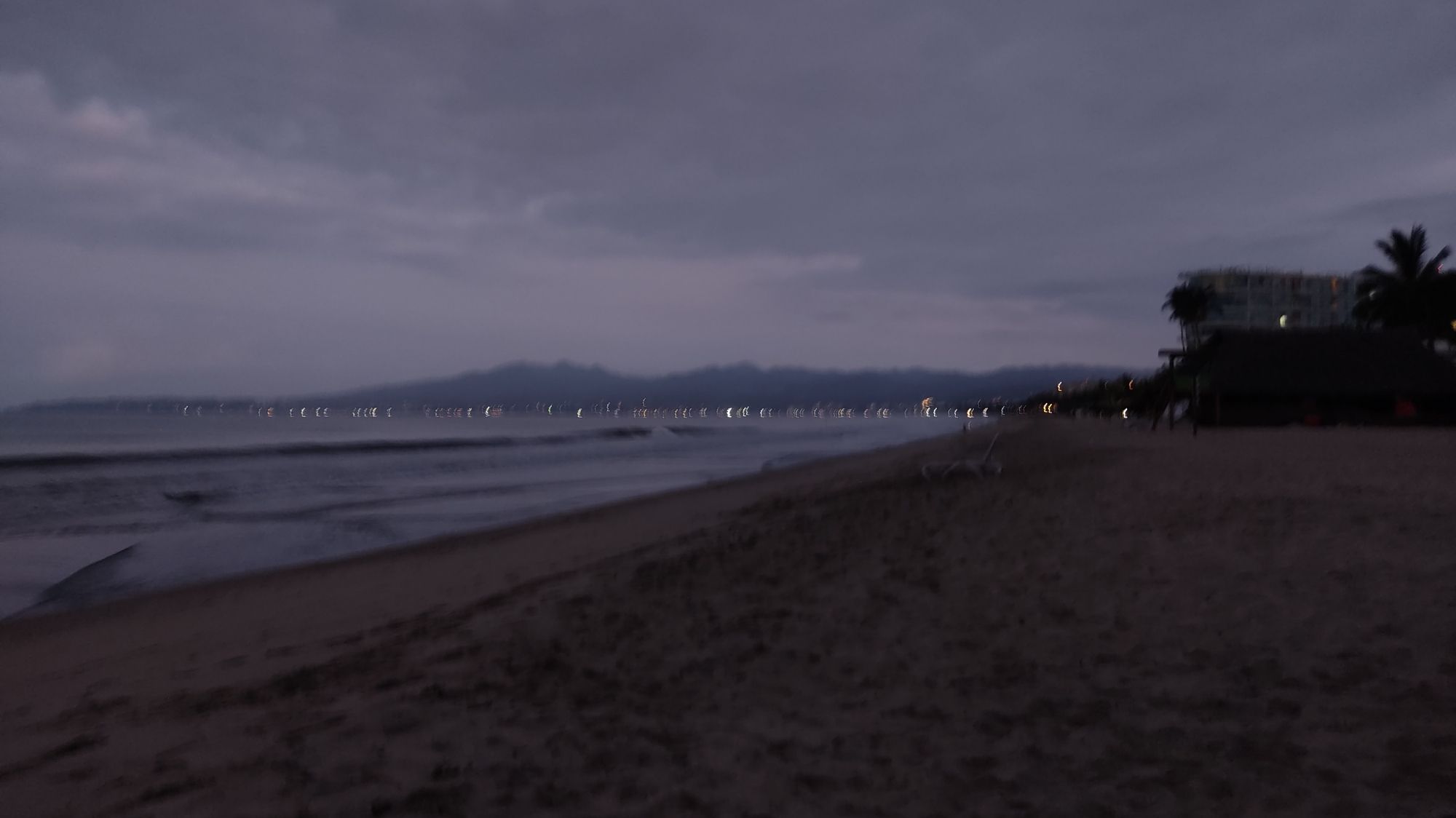 Blurry photo of a shoreline with a cloudy sky, early in the morning