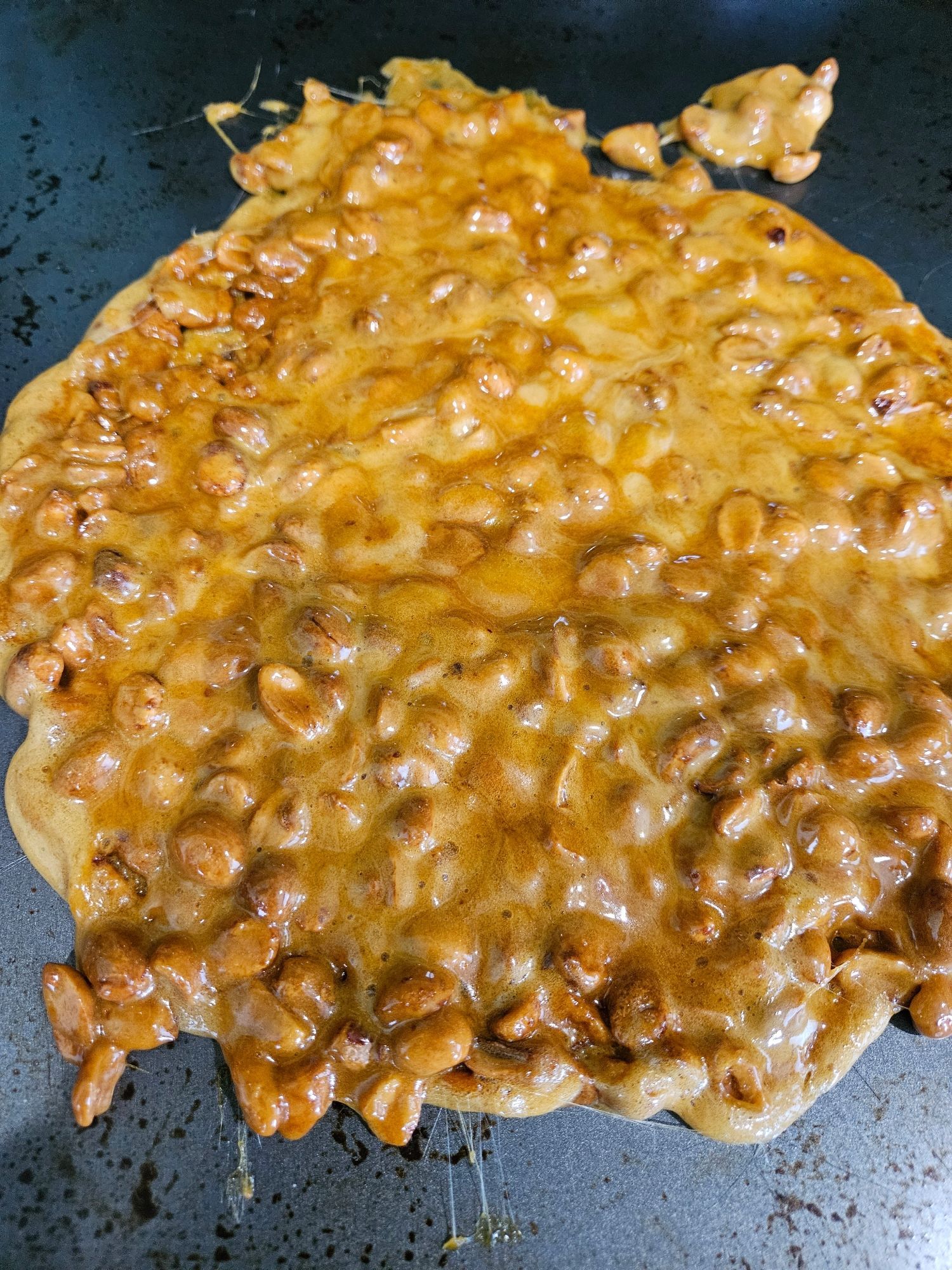 Tray of fresh peanut brittle cooling on a cookie sheet.