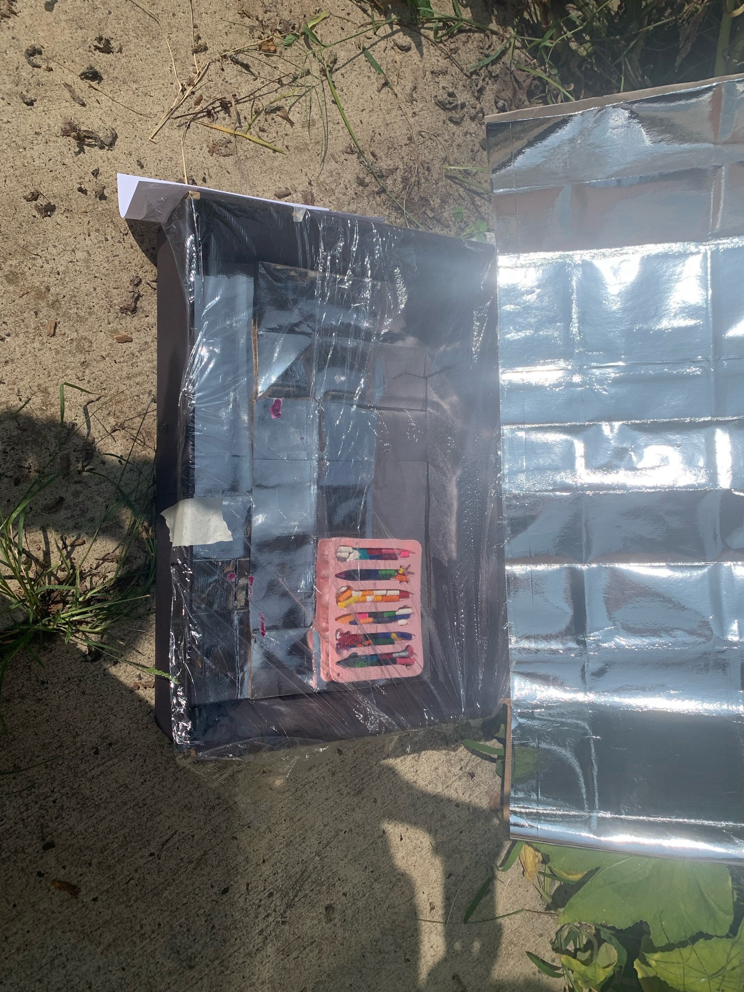 Crayon mold in a solar oven made from a cardboard box w foil & plastic wrap