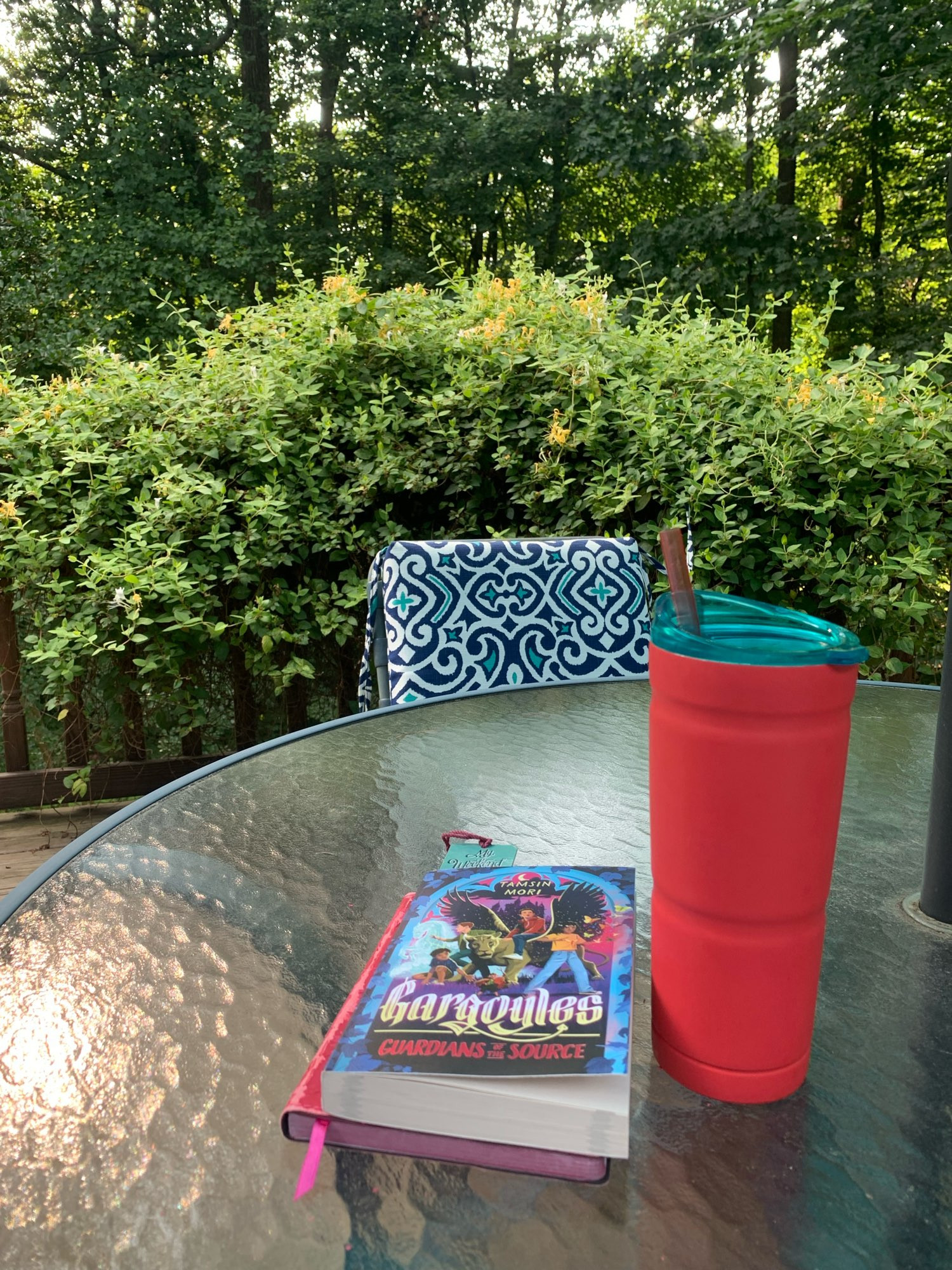 Patio table w books & iced coffee & honesuckle in the background.