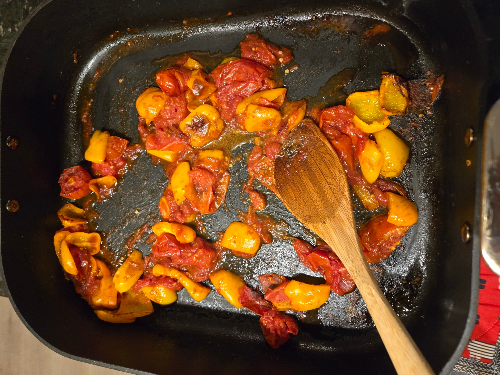 A roasting pan with bell peppers and Roma tomatoes