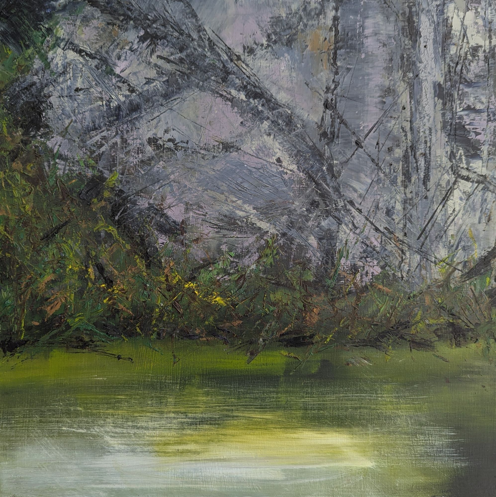 Quarry walls with foliage in the mid ground and  water with reflected sunlight in the foreground. 