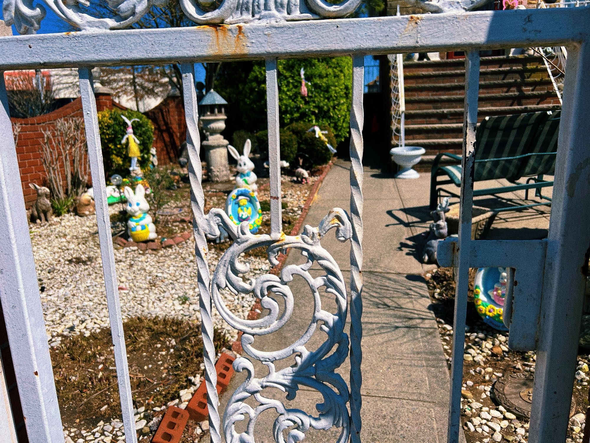 Easter decorations on a front lawn behind a white painted wrought iron fence.