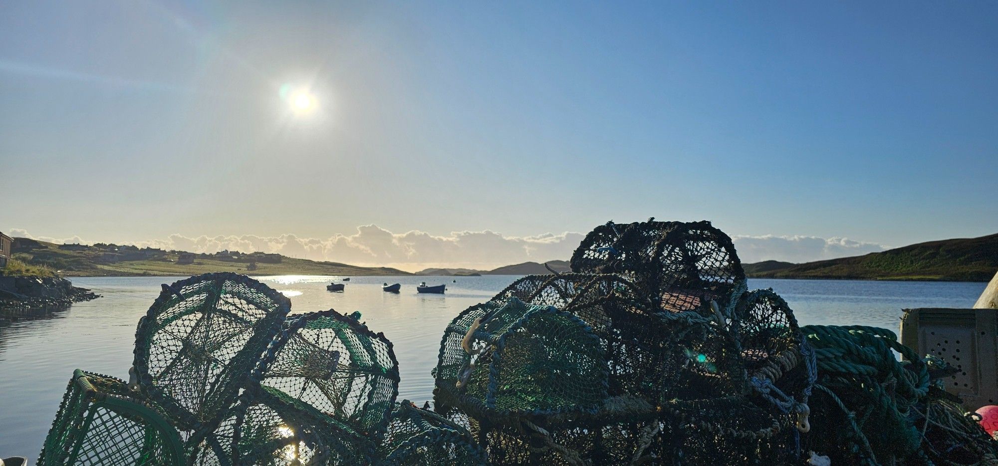 Loch Leurbost with three boats, and crab/lobster creels sitting on the pier.