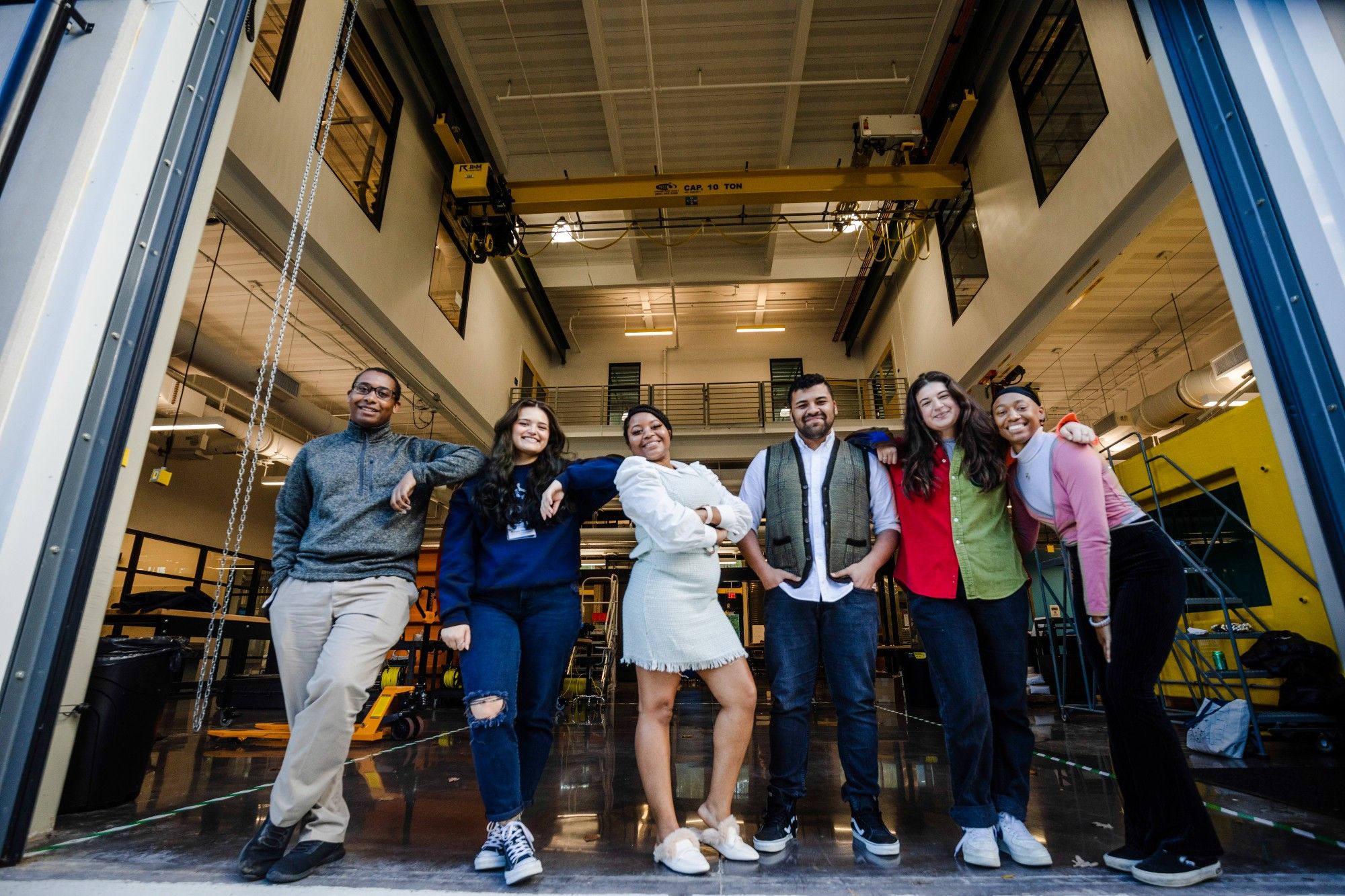 Six C-CoMP Bridge-to-PhD Fellows stand and pose in front of a research bay at Woods Hole Oceanographic Institution's David Center. Photo by Daniel Hentz, WHOI.