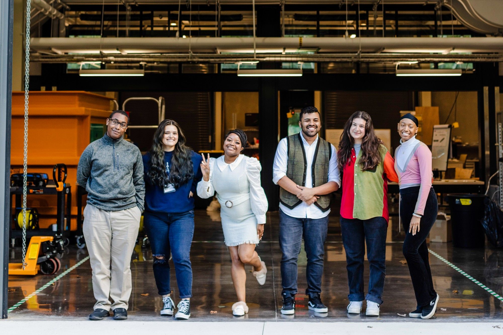 Six C-CoMP Bridge-to-PhD Fellows stand and pose in front of a research bay at Woods Hole Oceanographic Institution's David Center. Photo by Daniel Hentz, WHOI.