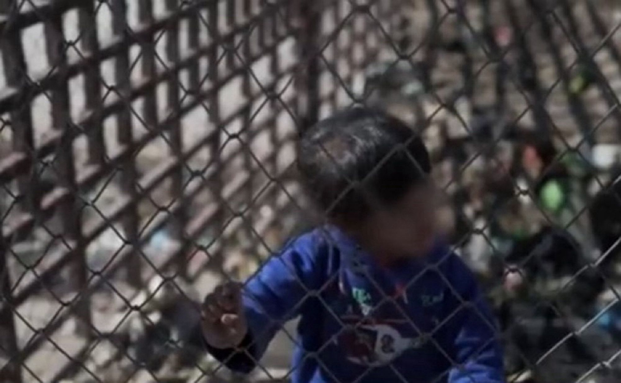 Des enfants derrière les grilles d’un camp.